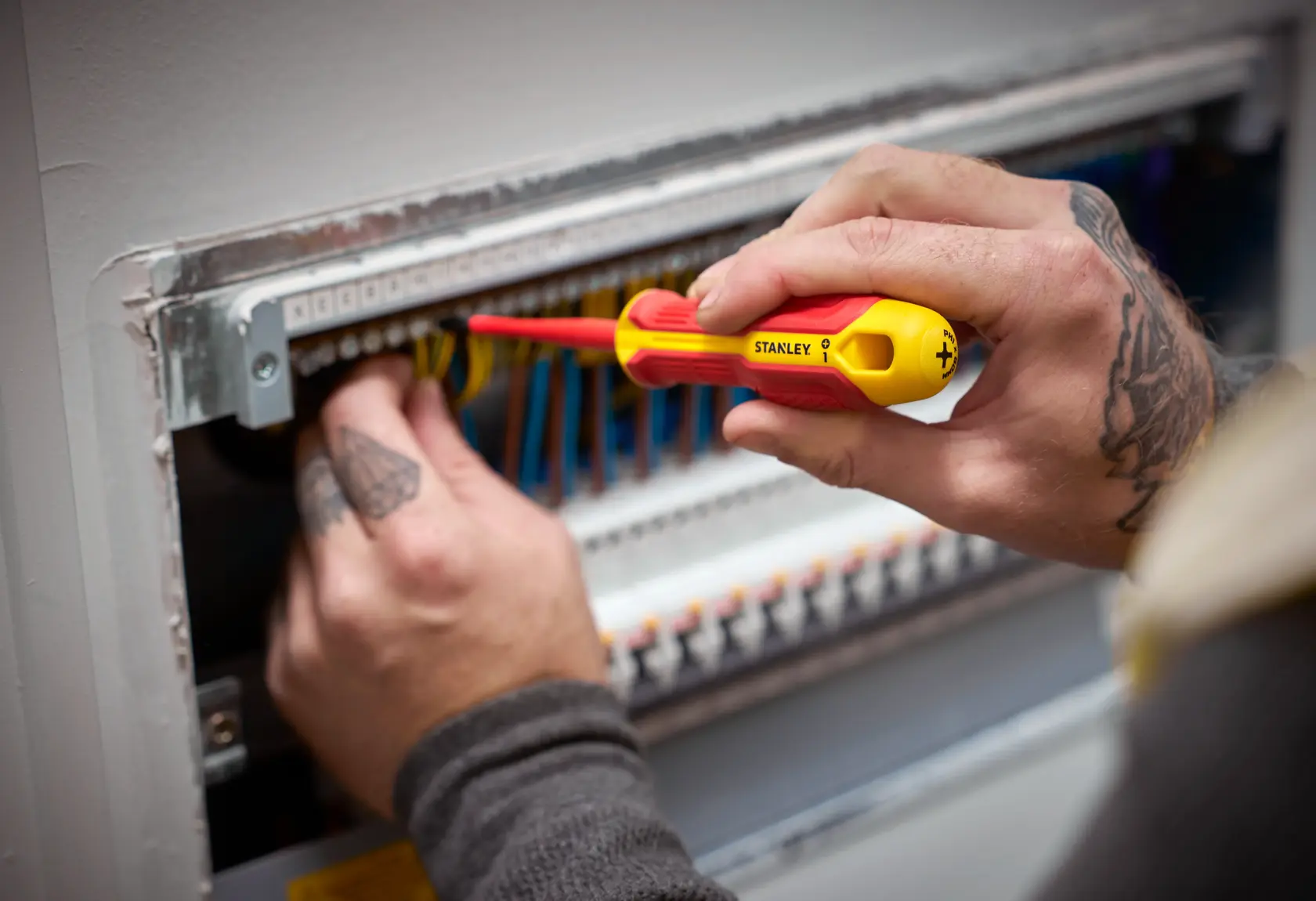 Person arbeitet mit einem STANLEY isolierten Schraubendreher an elektrischen Leitungen im Panel.