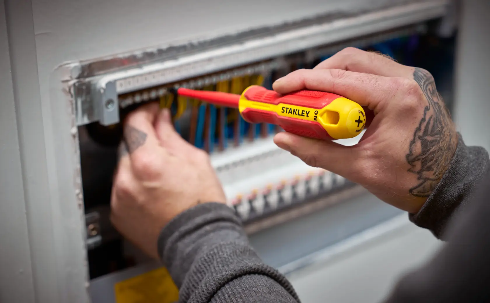 Person arbeitet mit STANLEY isoliertem Schraubendreher an elektrischen Leitungen im Schaltschrank.