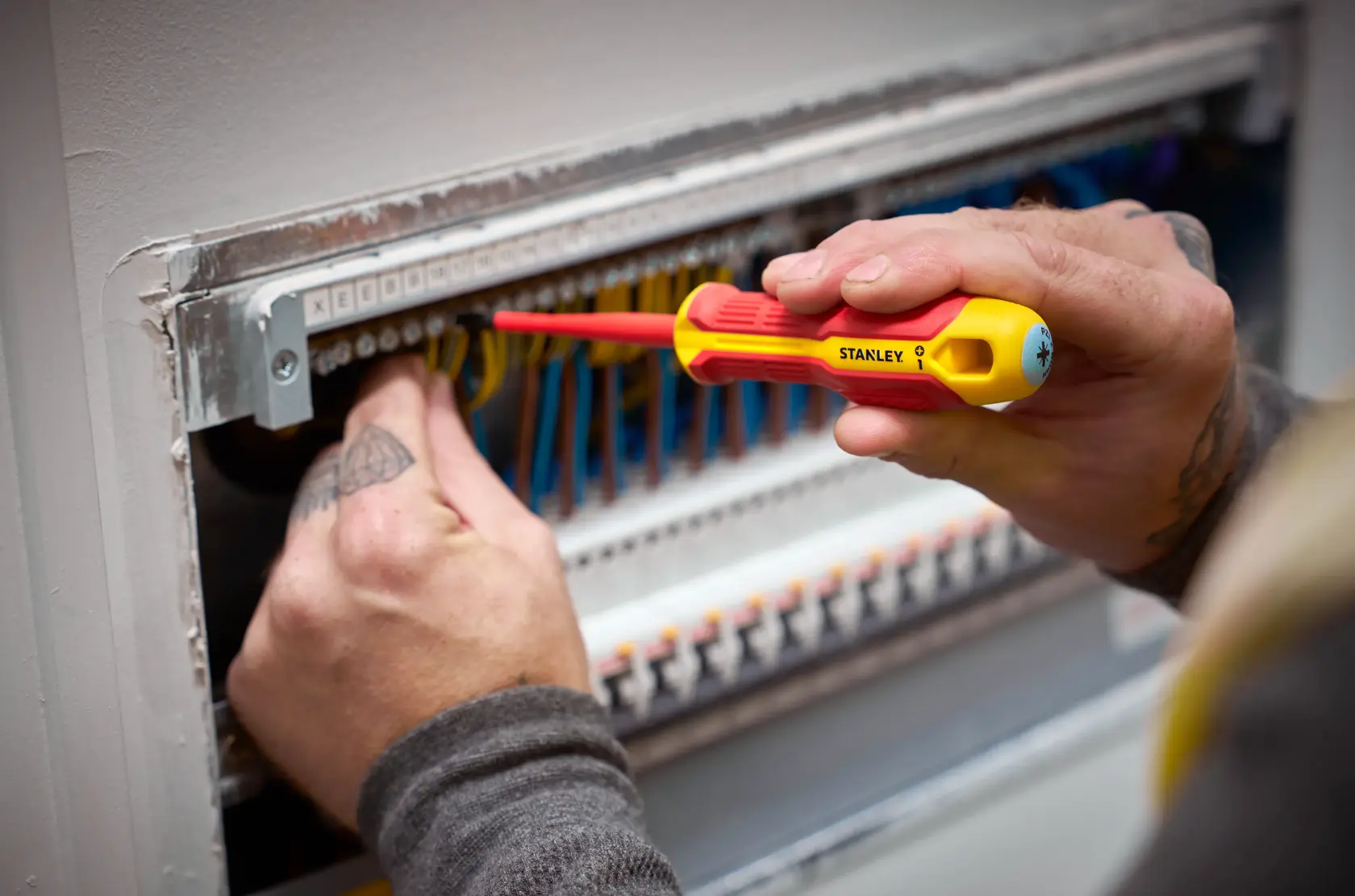 Person arbeitet mit STANLEY isoliertem Schraubendreher an Elektroverdrahtung im Schaltschrank.