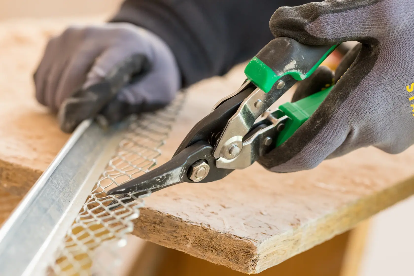 STANLEY FMHT73557-0 aviation snips cutting metal mesh, close-up angle, worker wearing gloves.