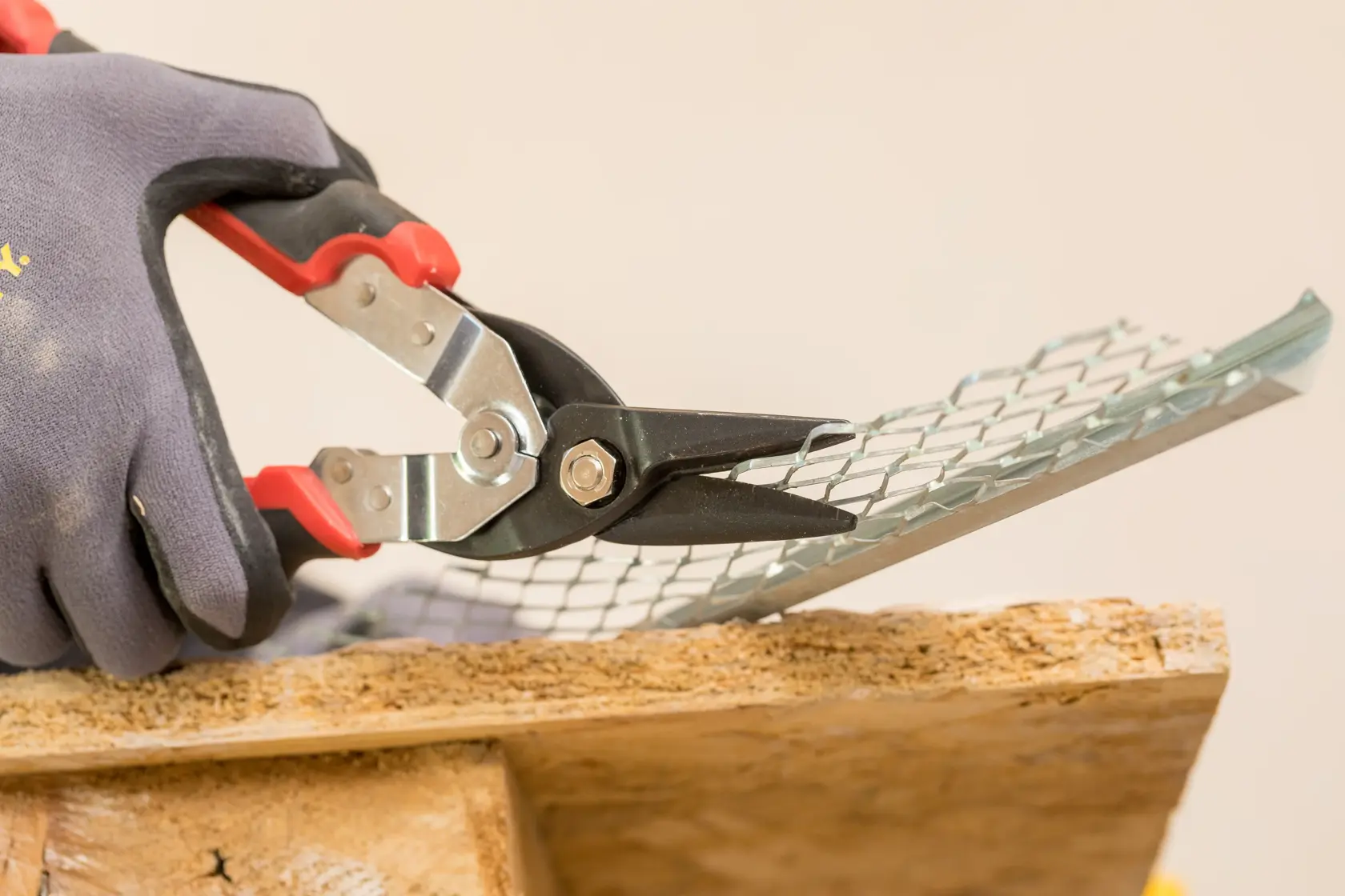 STANLEY FMHT73755 Blechschere schneidet Metallgitter, Nahaufnahme mit Handschuh.