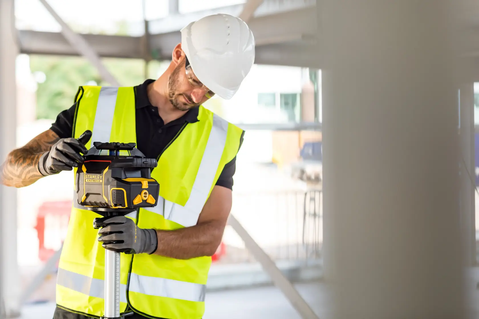 Foto des STANLEY FMHT77446-1 Rotationslaser-Niveaus, von einem Arbeiter mit Warnweste auf Baustelle genutzt.