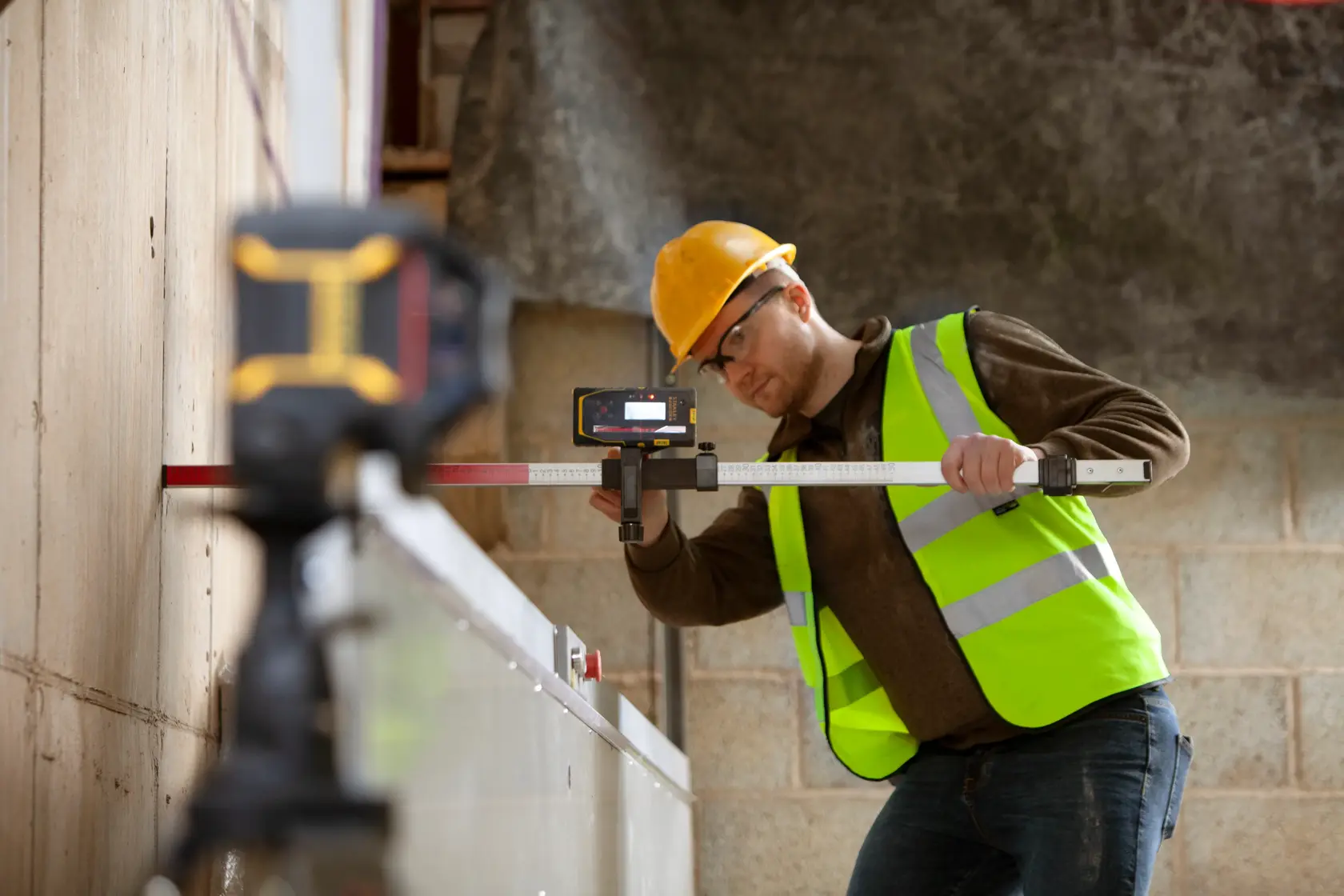 STANLEY FMHT77652-0 Laser-Nivelliergerät im Einsatz auf Baustelle von Arbeiter mit Warnweste.