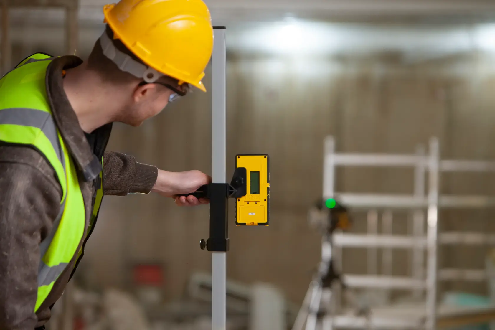 Foto eines Arbeiters mit einem STANLEY FMHT77653-0 Laserdetektor, der an einer Stange auf einer Baustelle befestigt ist.