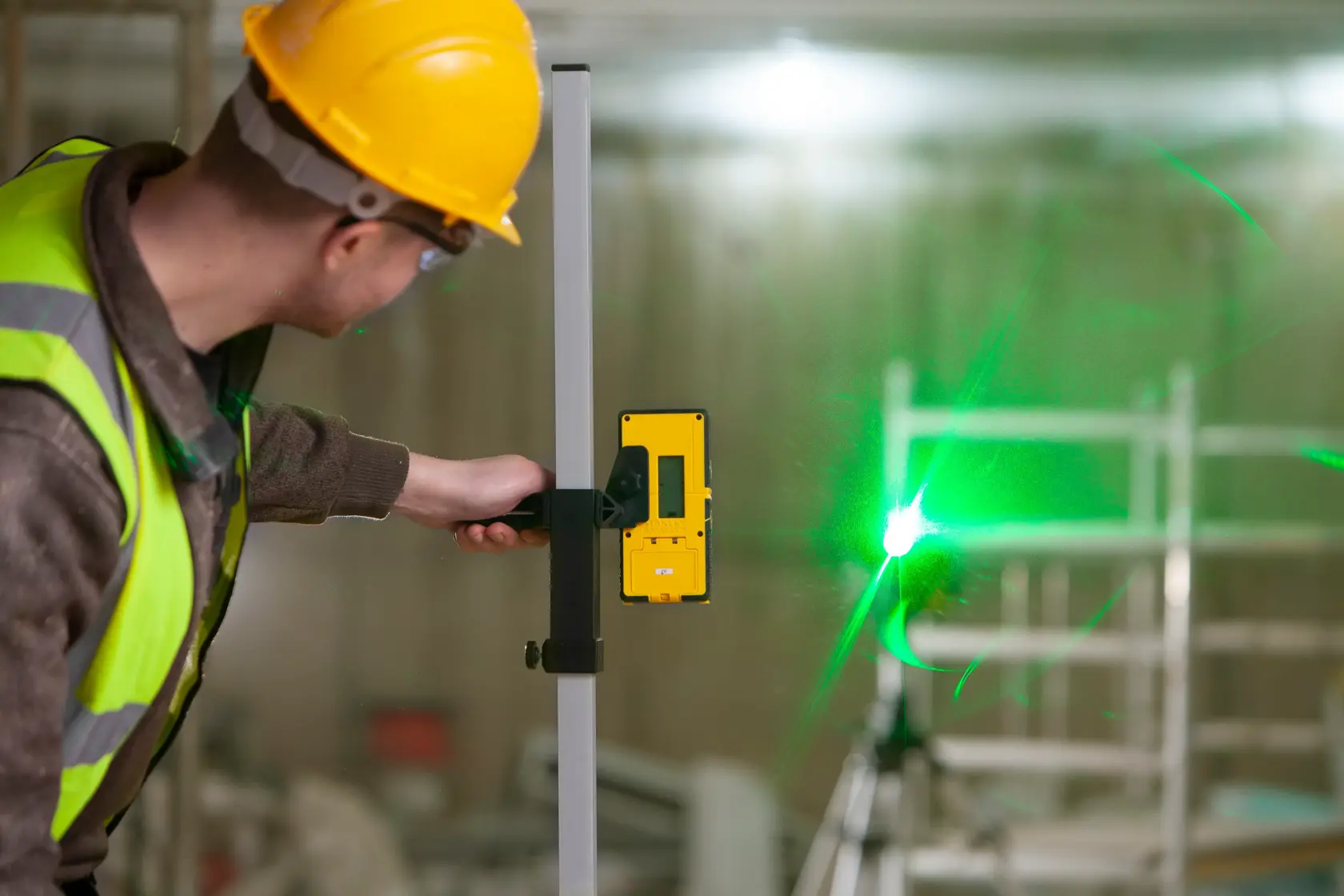 STANLEY FMHT77653-0 Laserdetektor von Arbeiter gehalten neben grünem Laserstrahl, Baustelle.