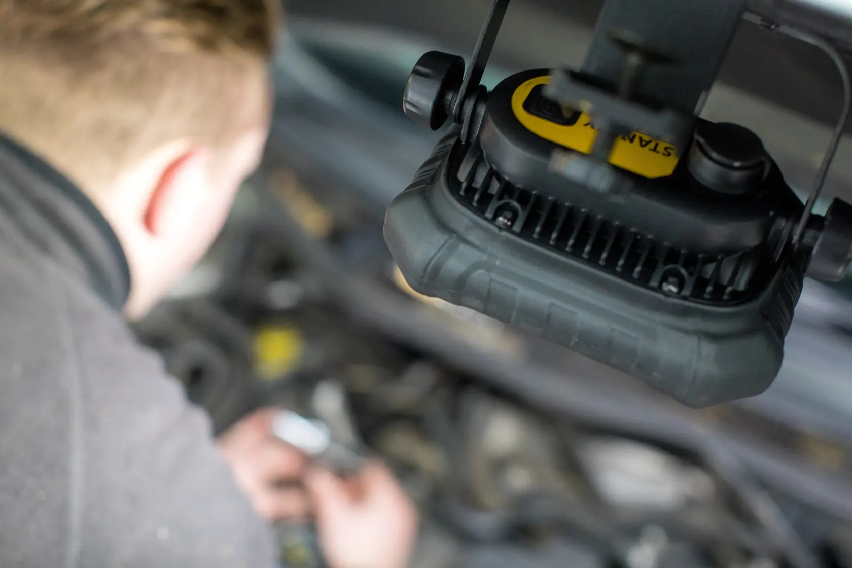 STANLEY FMHT81507-1 Arbeitsleuchte über einem Auto-Motor im Einsatz, Nahaufnahme Fotografie.