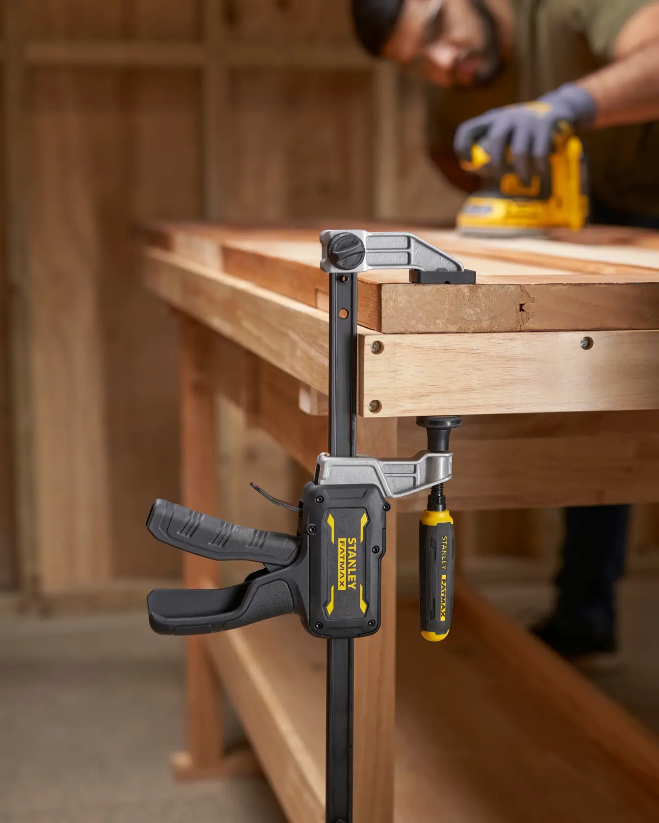 STANLEY FMHT83006-0 Schraubzwinge mit gelbem und schwarzem Griff an Holzwerkbank, seitliche Aufnahme.
