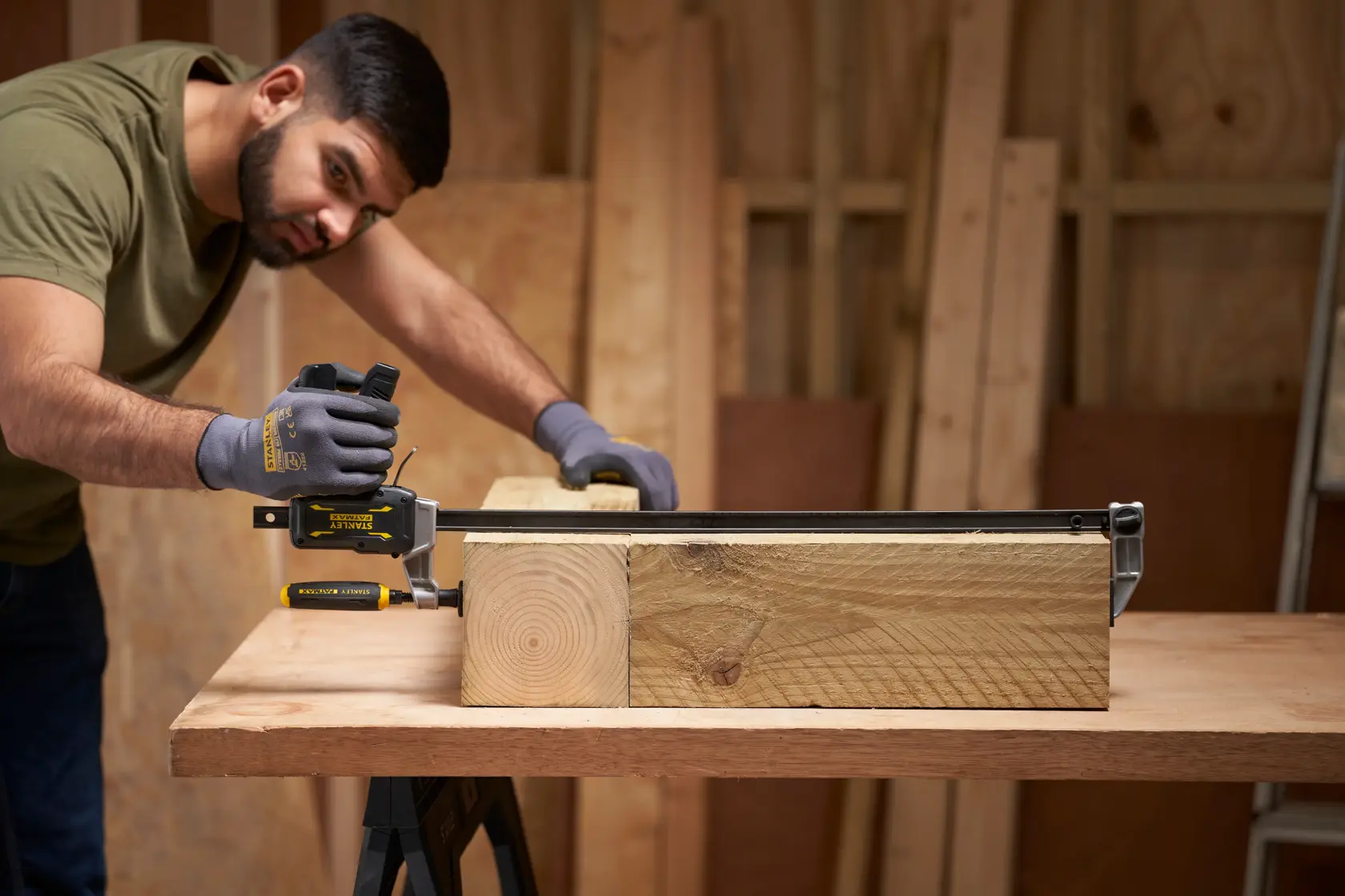 STANLEY FMHT83008-0 Zwinge hält dicken Holzbalken auf Werkbank in Werkstattumgebung.