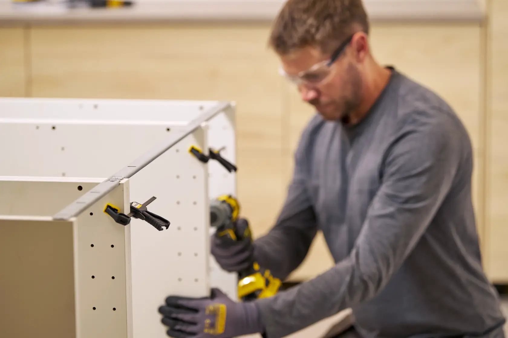 STANLEY FMHT83270-0 Schraubzwingen sichern weiße Schrankplatten bei der Montage, Nahaufnahme, Werkstatt.