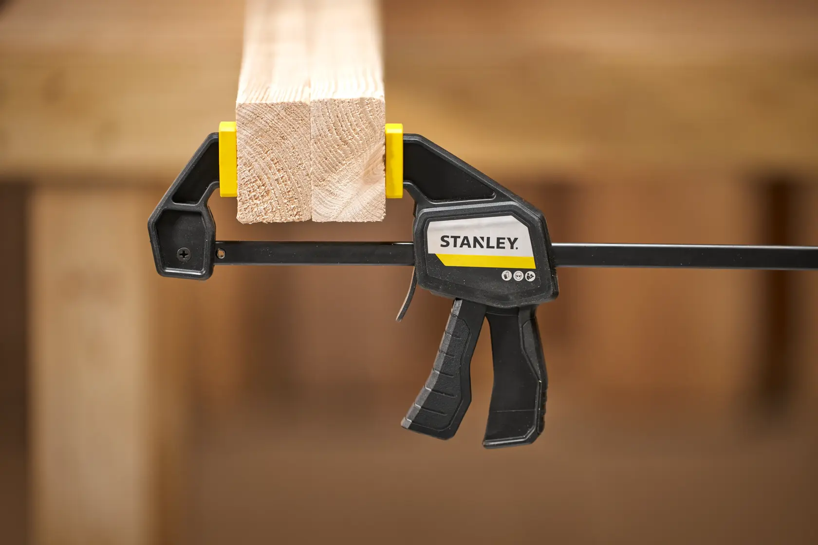 STANLEY FMHT83271-0 Schnellspannzwinge hält Holzträger, Produkt Seitenansicht, Kontext Holzarbeiten.
