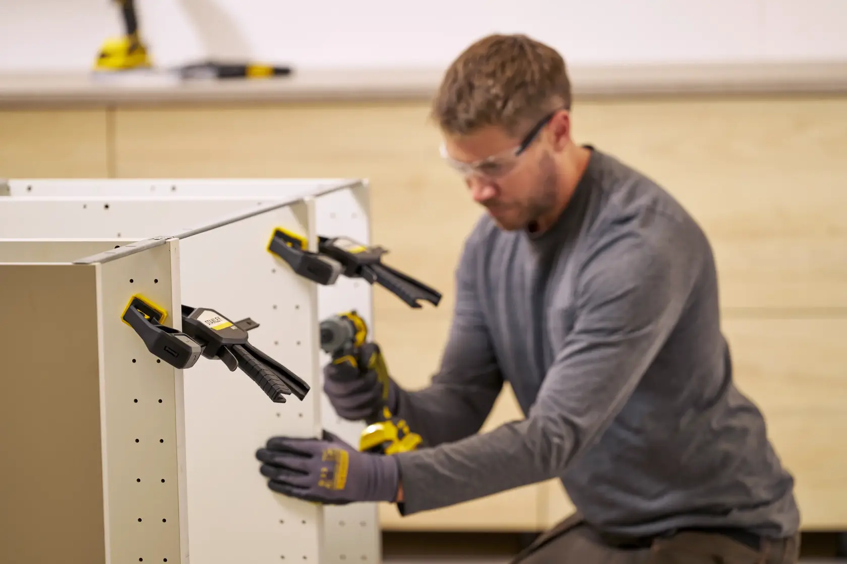 STANLEY FMHT83273-0 Zwingen halten weiße Schrankplatten bei der Montage, Nahaufnahme, Werkstattumgebung.