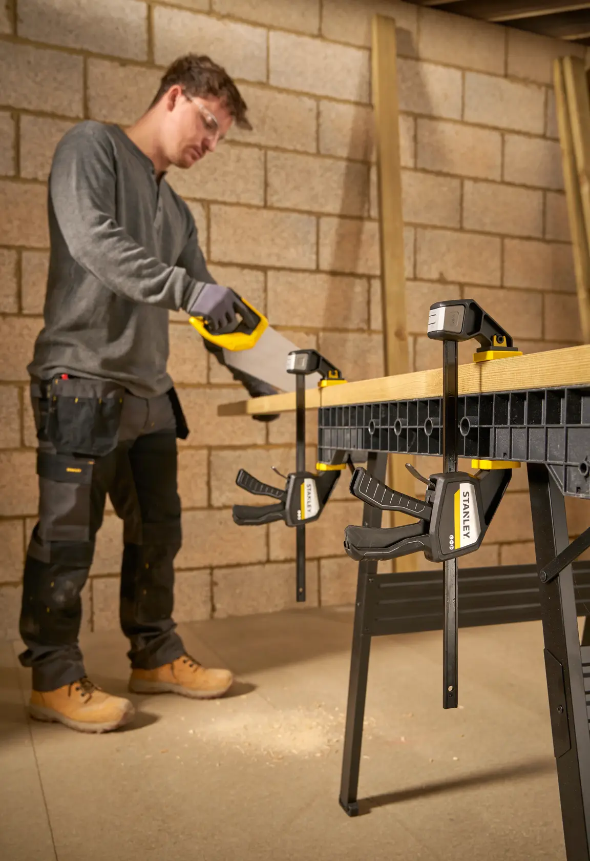Fotografie von STANLEY FMHT83274-0 Klemme, die Holz auf Werkbank beim Sägen im Werkraum sichert.