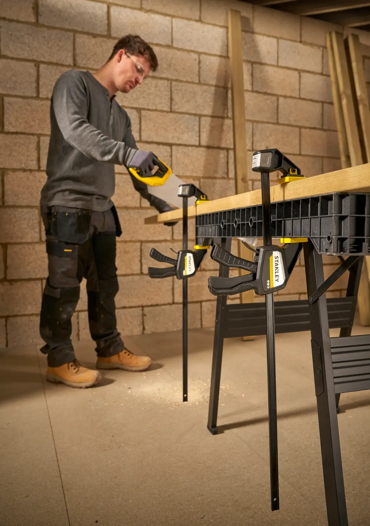 Foto von STANLEY FMHT83276-0 Schraubzwingen, die Holz auf Werkbank im Einsatz durch Arbeiter sichern.