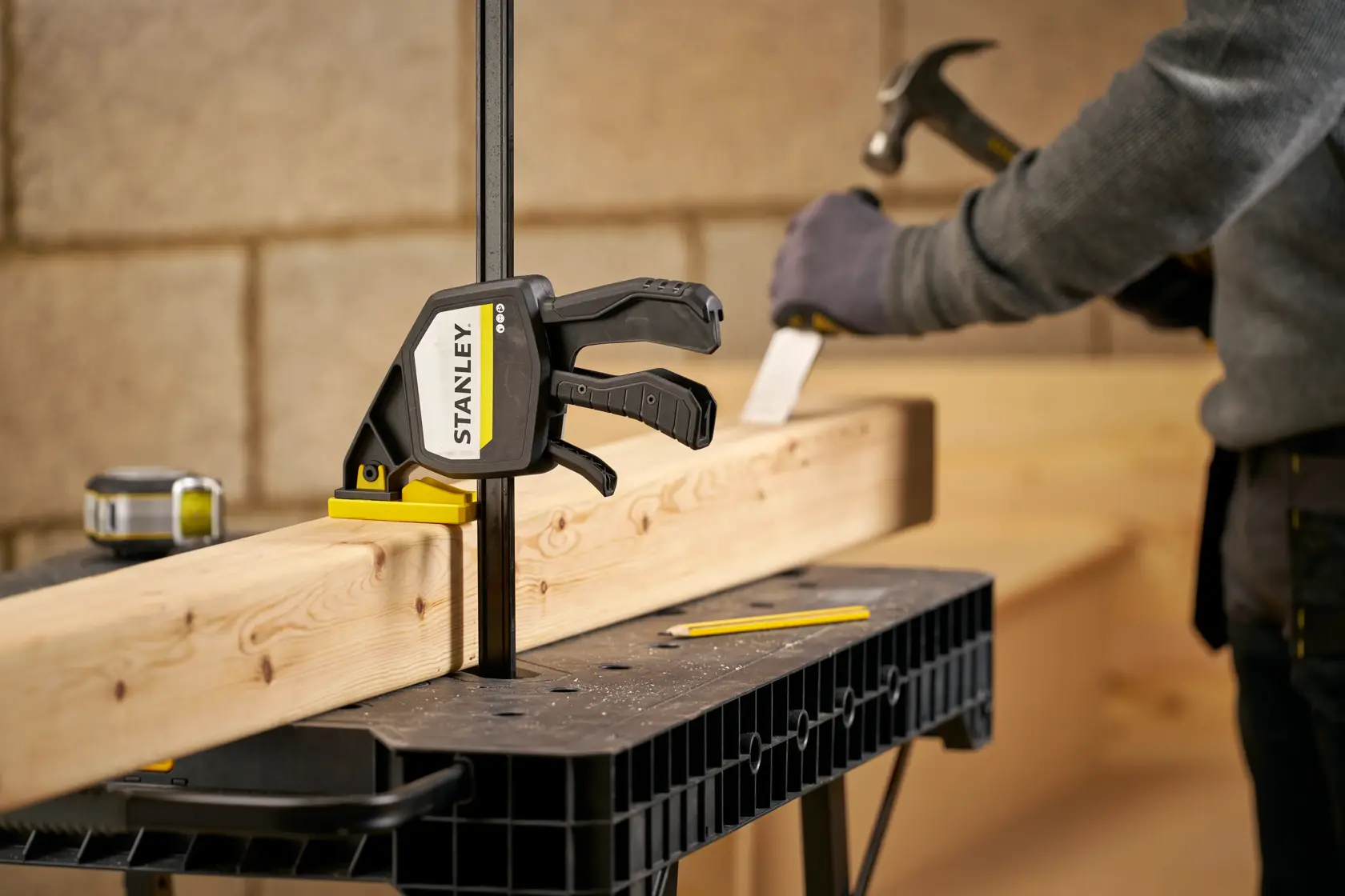 Foto der STANLEY FMHT83280-0 Schraubzwinge, die Holz auf einer Werkbank hält, Person im Hintergrund.