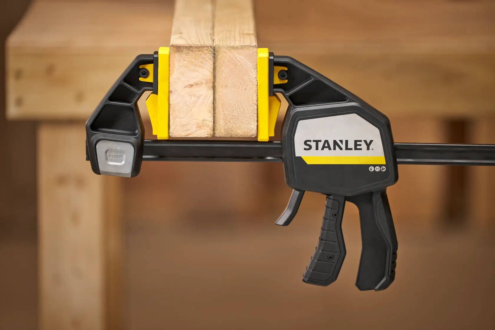Foto der STANLEY FMHT83282-0 Schnellspannzwinge, die Holzplatten am Arbeitstisch fixiert.