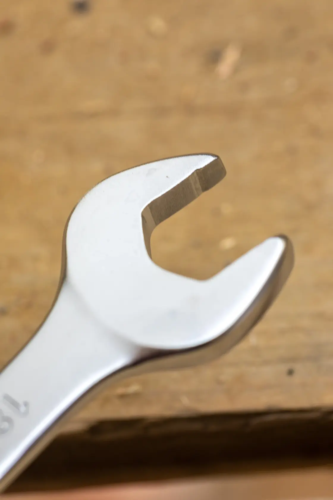 STANLEY FMMT13042-0 wrench close-up on wooden surface, silver open-end tool, photography category.