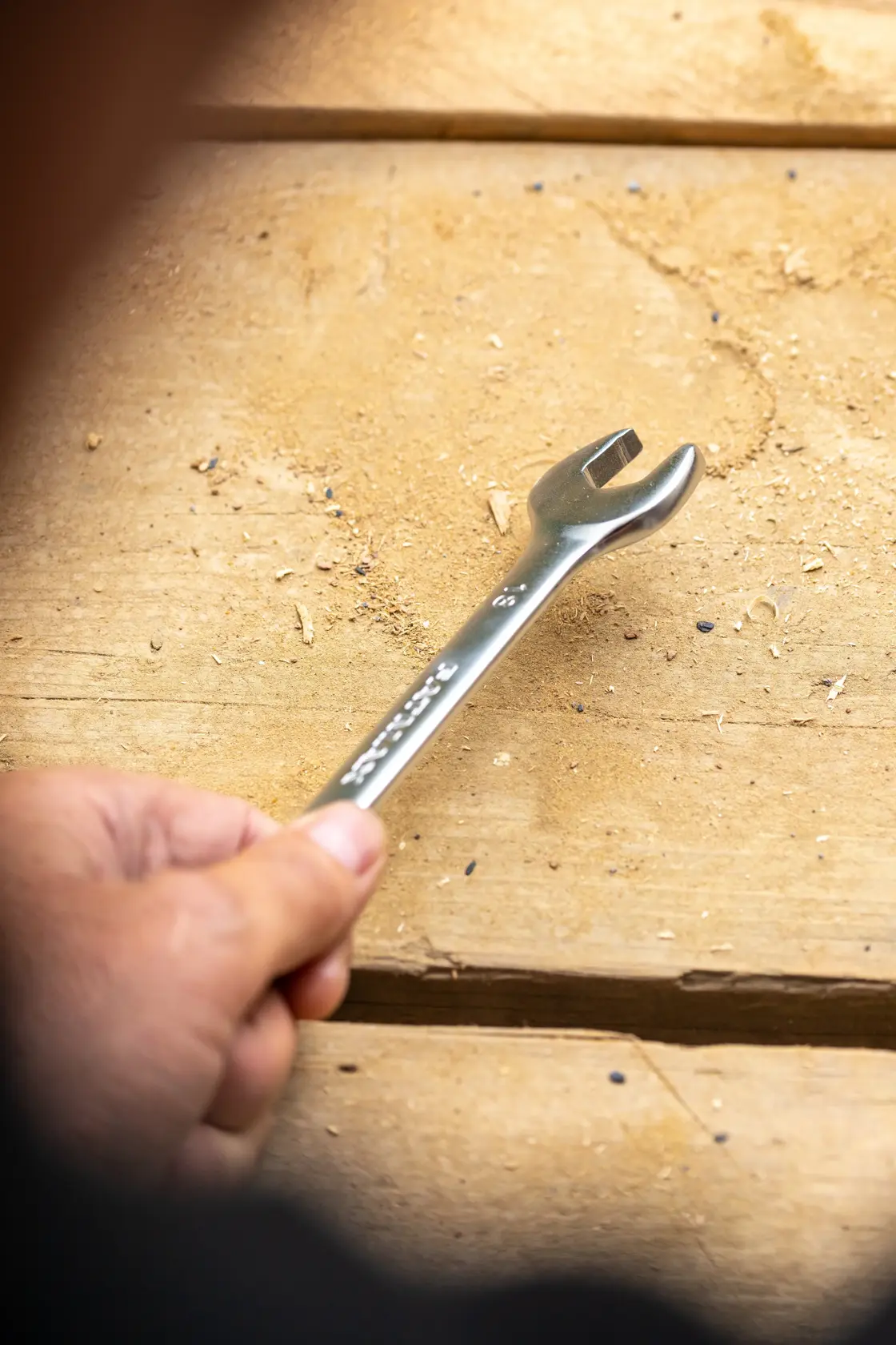 STANLEY FMMT13062-0 open end wrench held by hand on wooden surface, product photography.