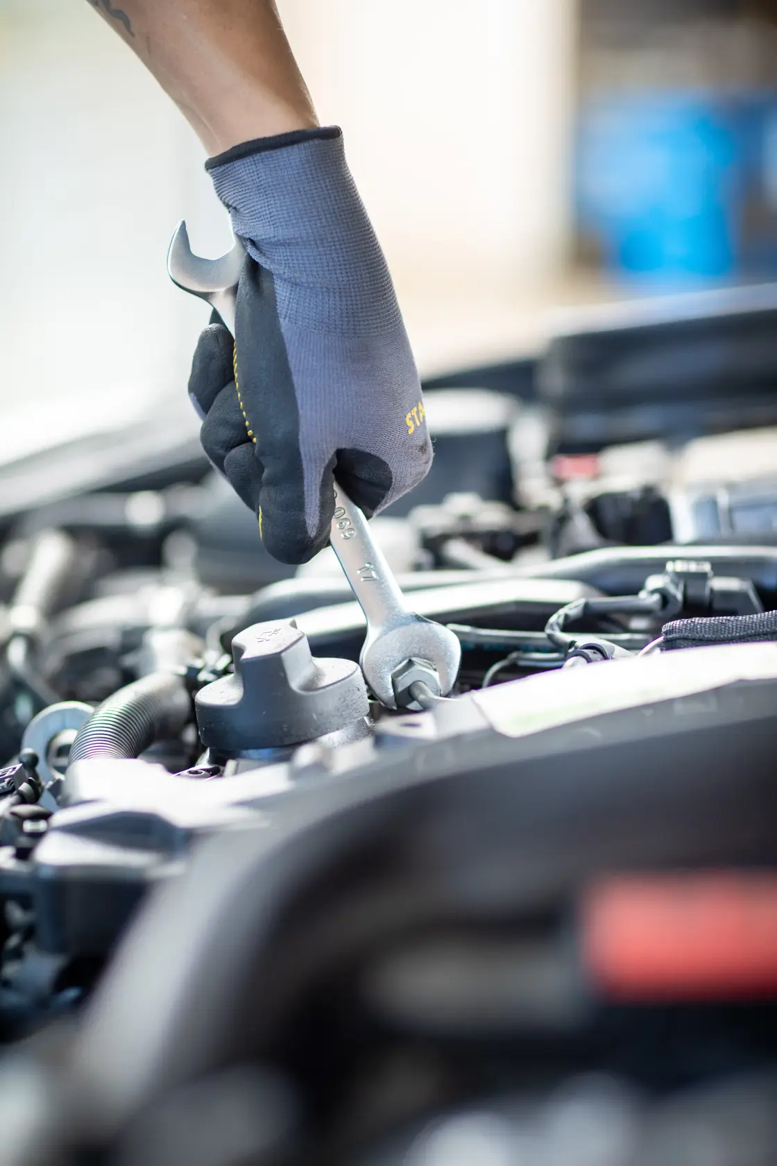 STANLEY FMMT13073-0 wrench in use on engine, mechanic wearing glove, close-up, photography.