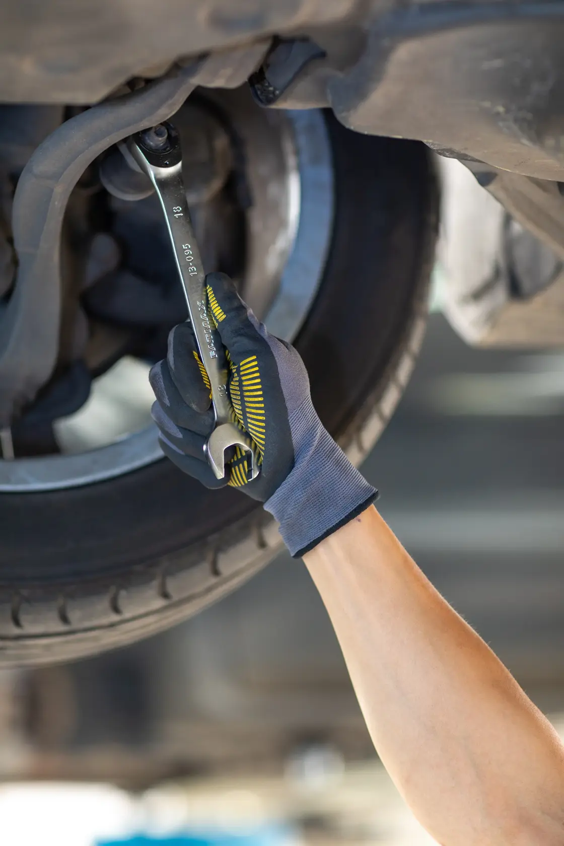 STANLEY FMMT13089-0 wrench used by gloved hand to repair car wheel, close-up photo.
