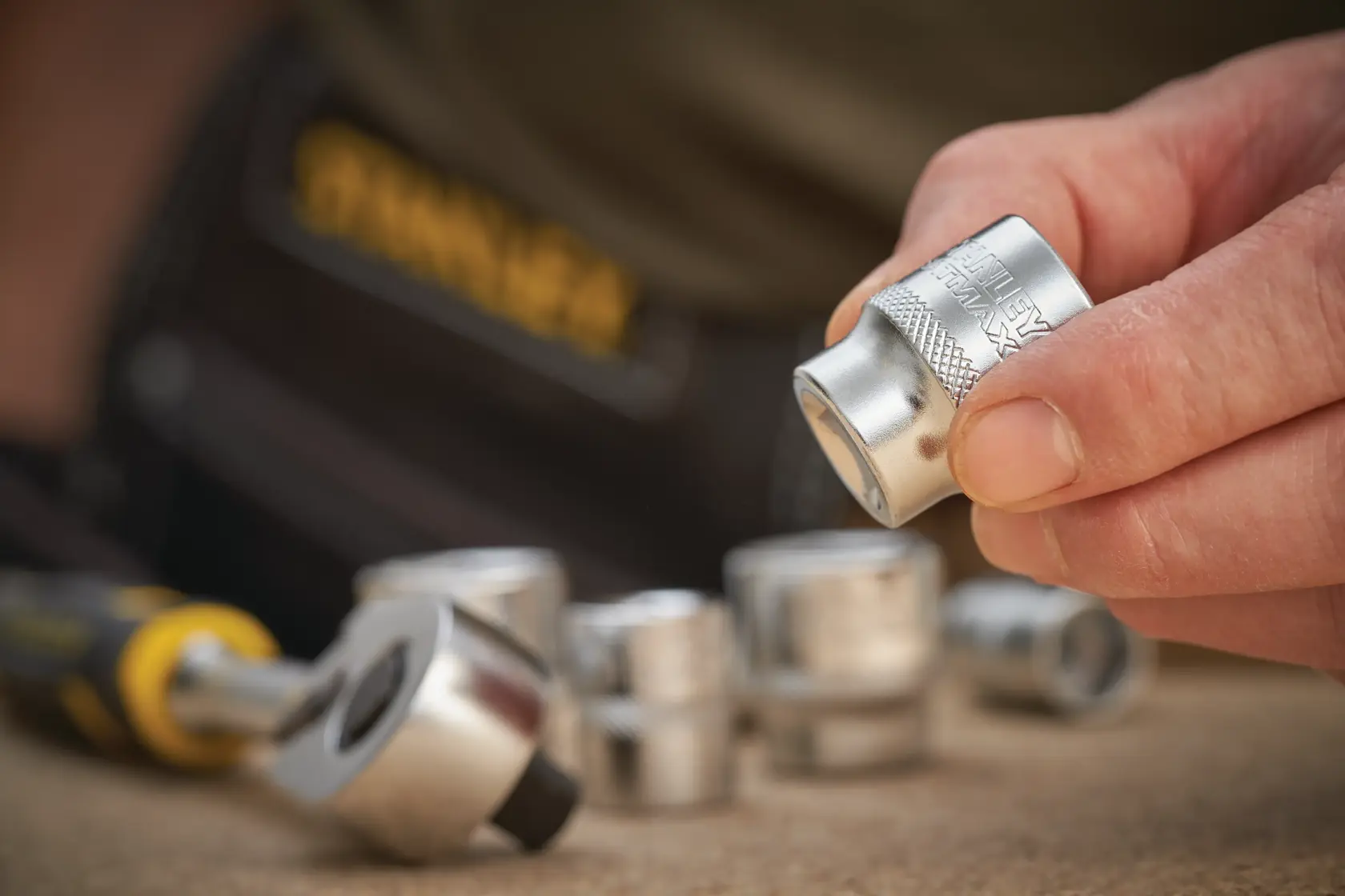 STANLEY FMMT17215-0 chrome socket set with ratchet, close-up of hand holding socket, Photography category.