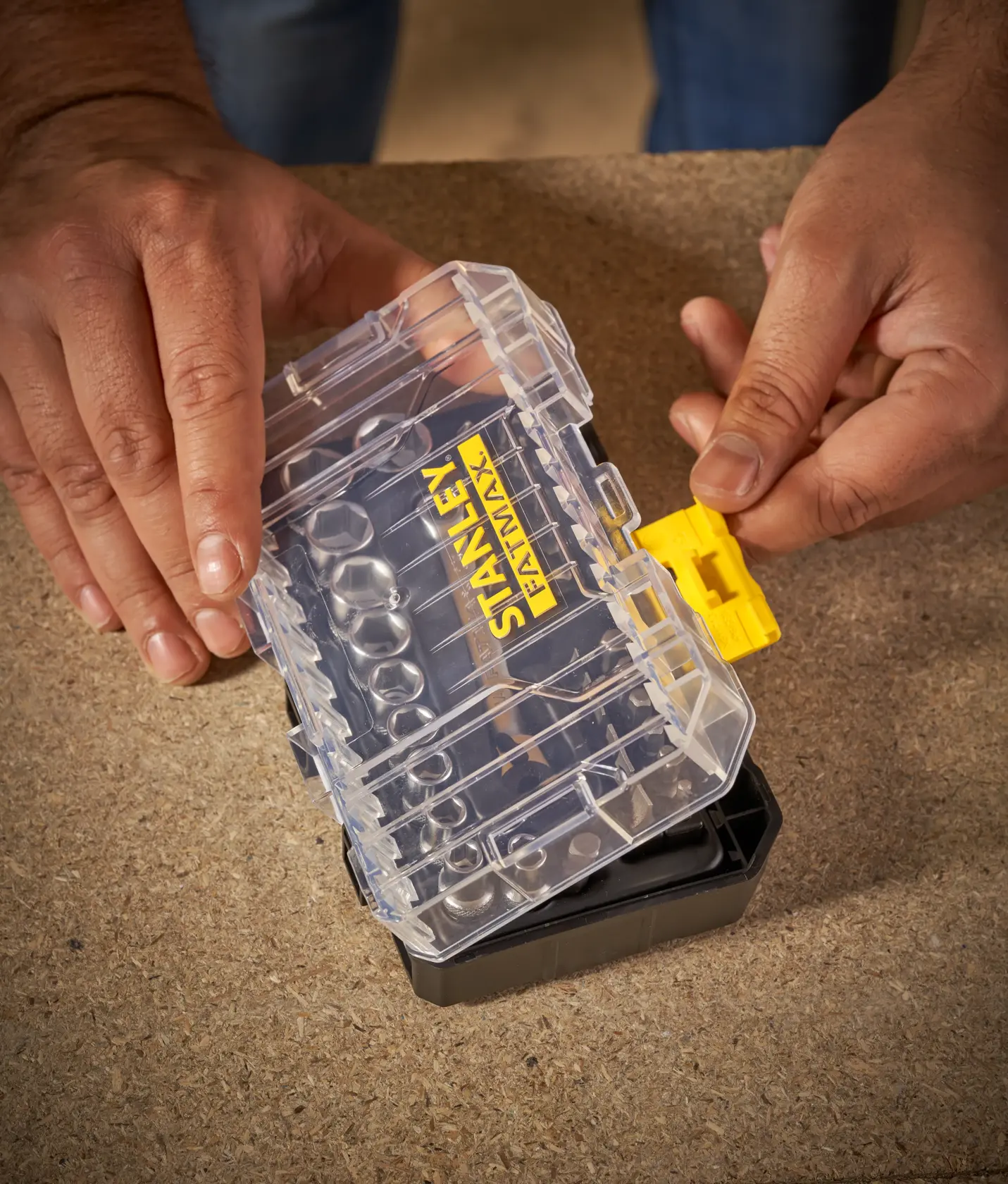 STANLEY FMMT19101-0 small organizer with clear lid and yellow latch, hands opening on workbench.