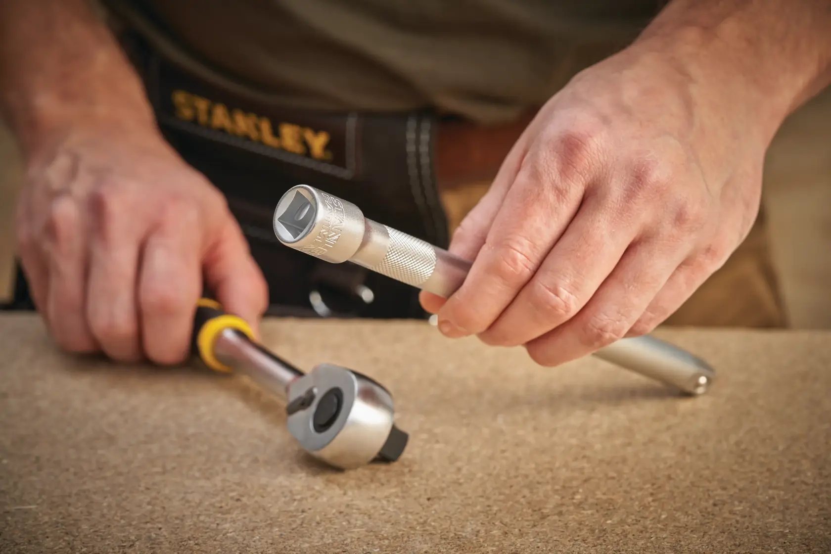 Stanley FMMT25122-0 ratchet and socket tool held by person, close-up on work surface.
