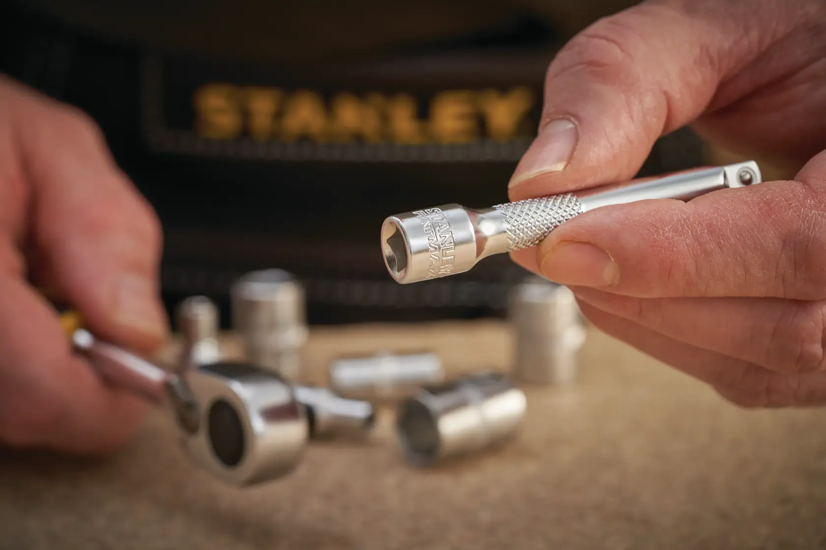 Photo of STANLEY FMMT25125-0 socket wrench and attachment held in hand with other sockets nearby.