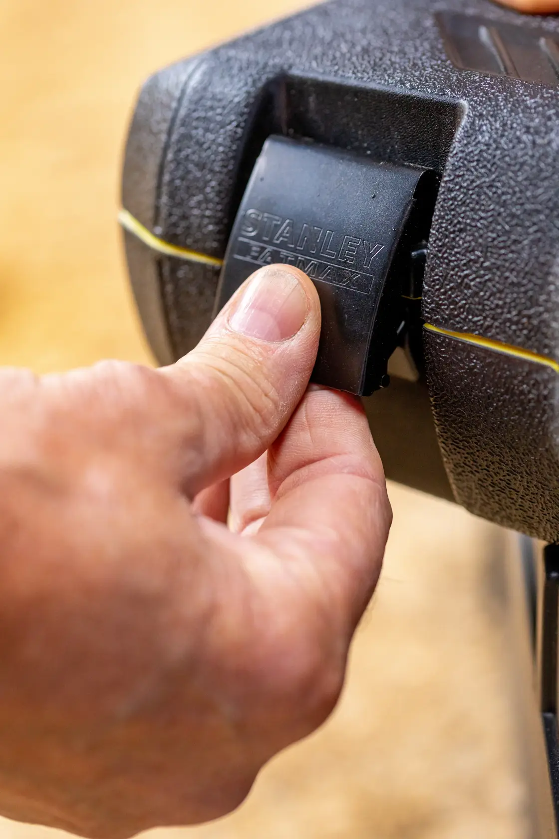 Photo of a hand opening the latch on a STANLEY toolbox, SKU FMMT82685-1, close-up view.