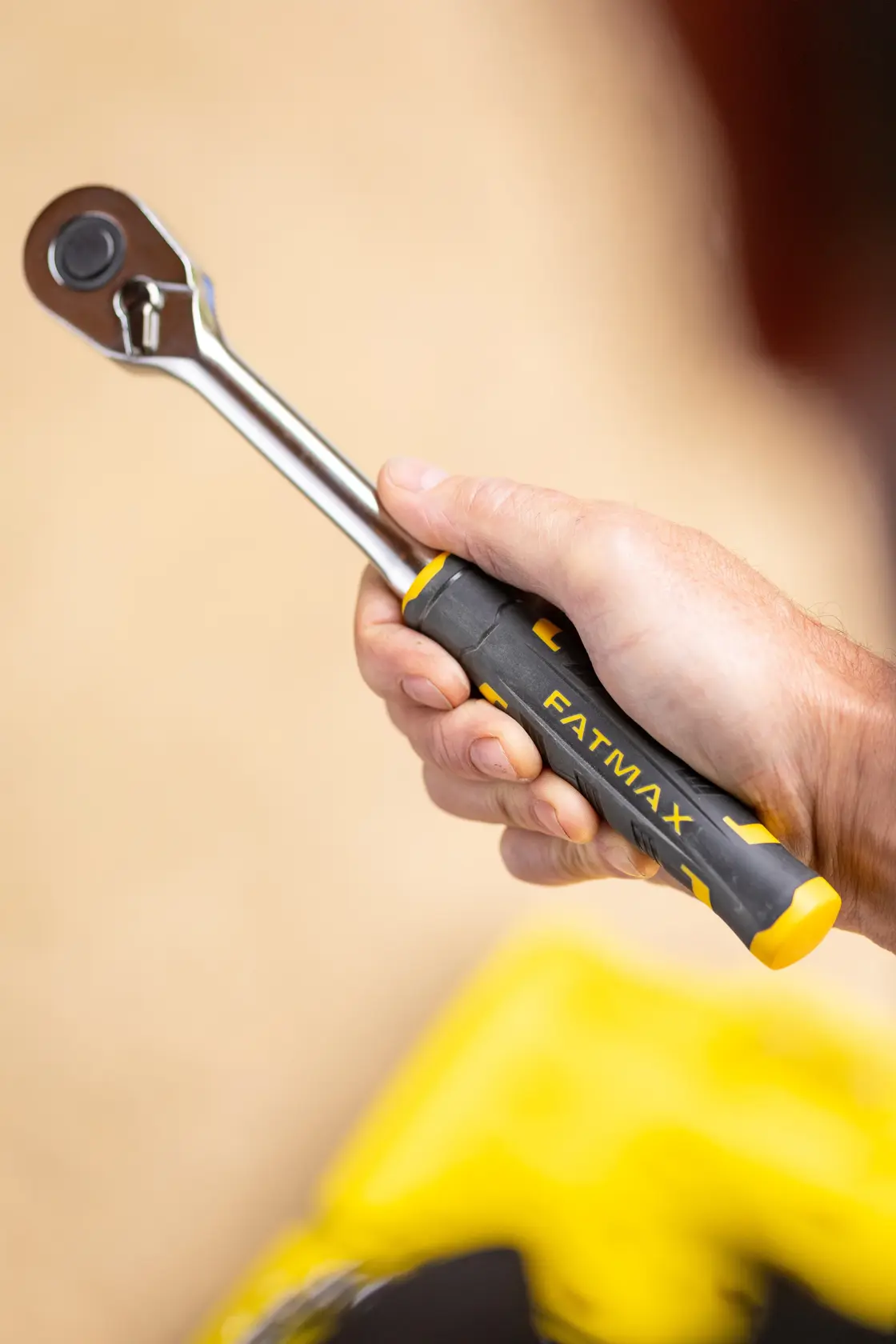 STANLEY FMMT82685-1 ratchet wrench with black and yellow FATMAX handle held in hand, side view.