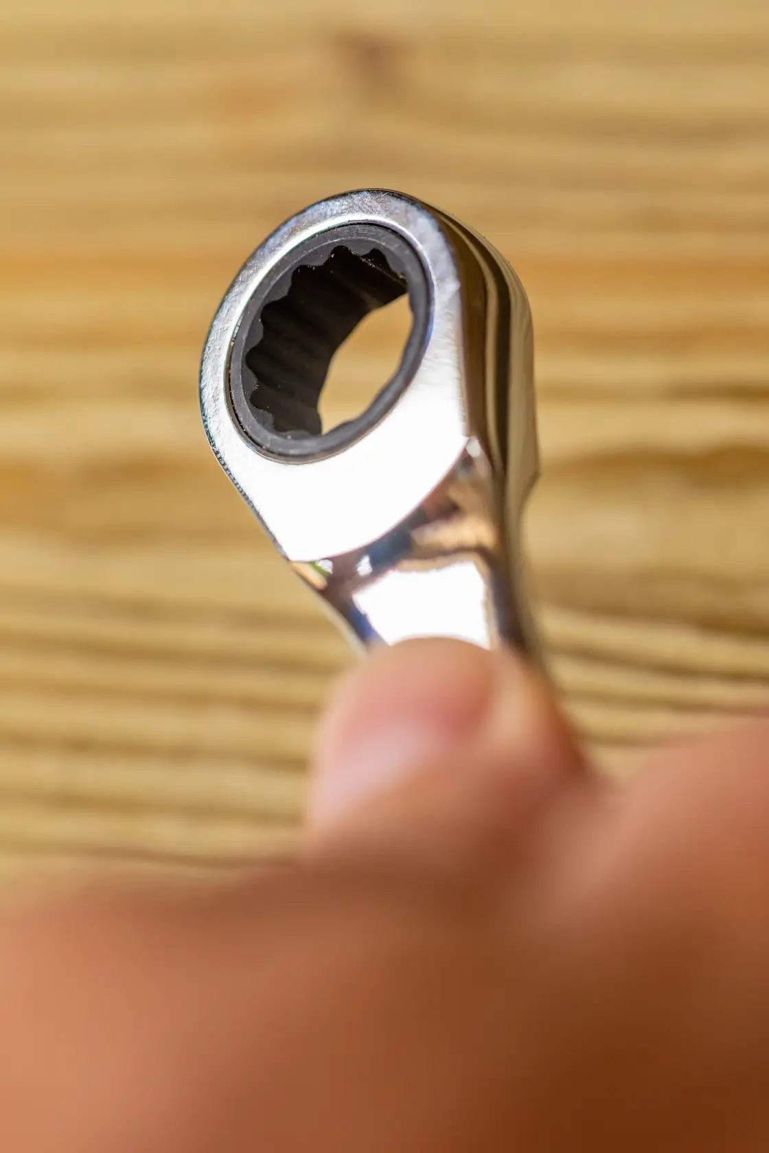 STANLEY FMMT82849-0 ratcheting wrench close-up in hand, silver finish, tool on wood background.