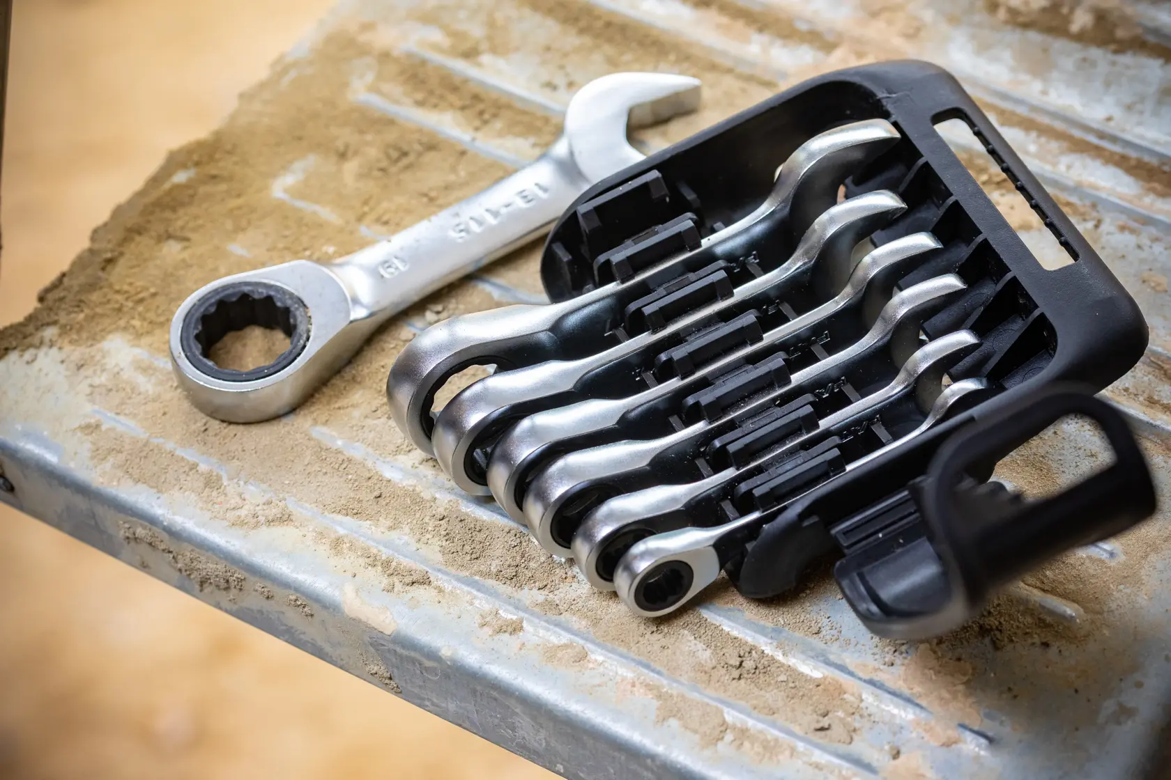STANLEY FMMT82900-0 ratcheting spanner set in black holder on metal surface with sand, angled outdoor view.