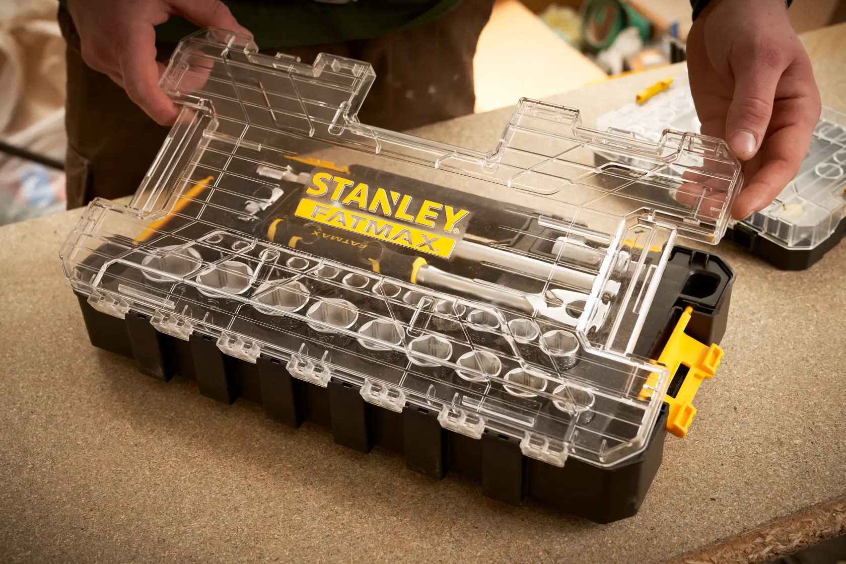STANLEY FMMT98103-1 organizer box with clear lid and FATMAX branding, held by hands, on a workbench.
