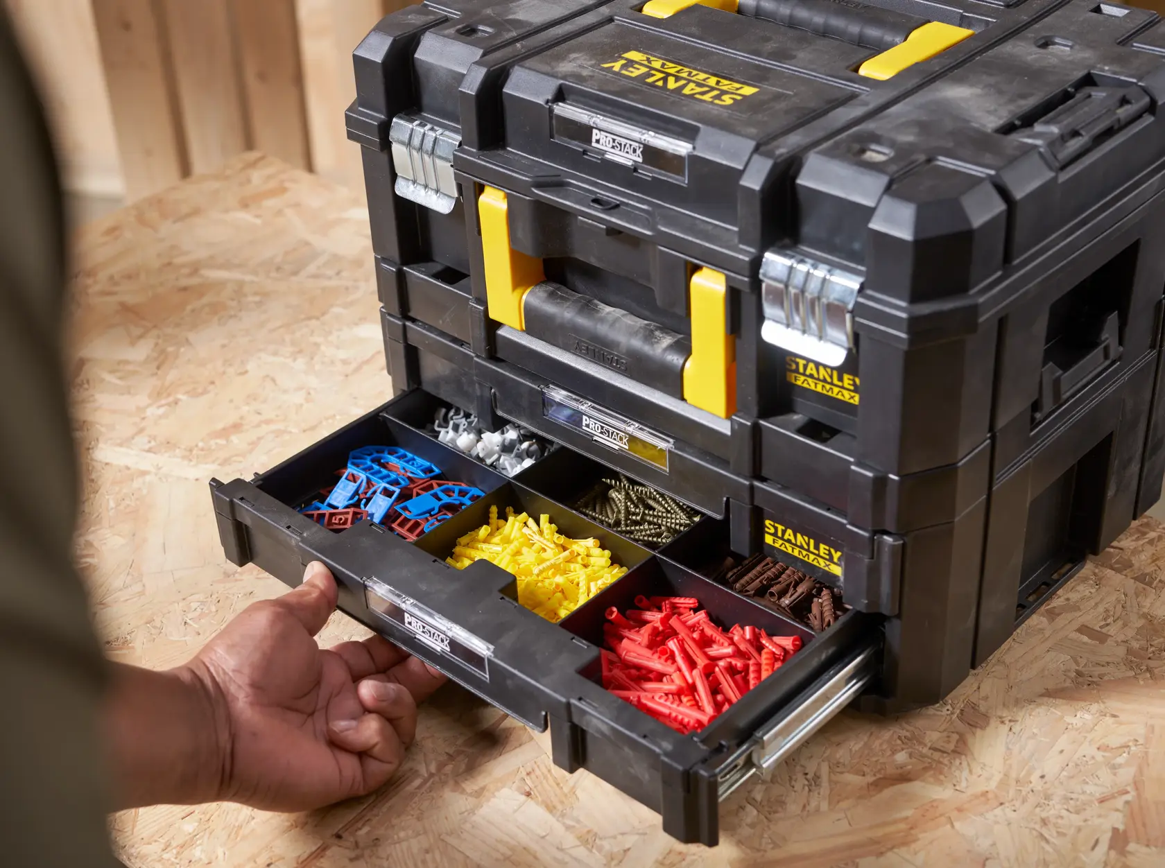 STANLEY FMST1-71981 organizer box with open drawer showing assorted hardware, black and yellow, front angle.