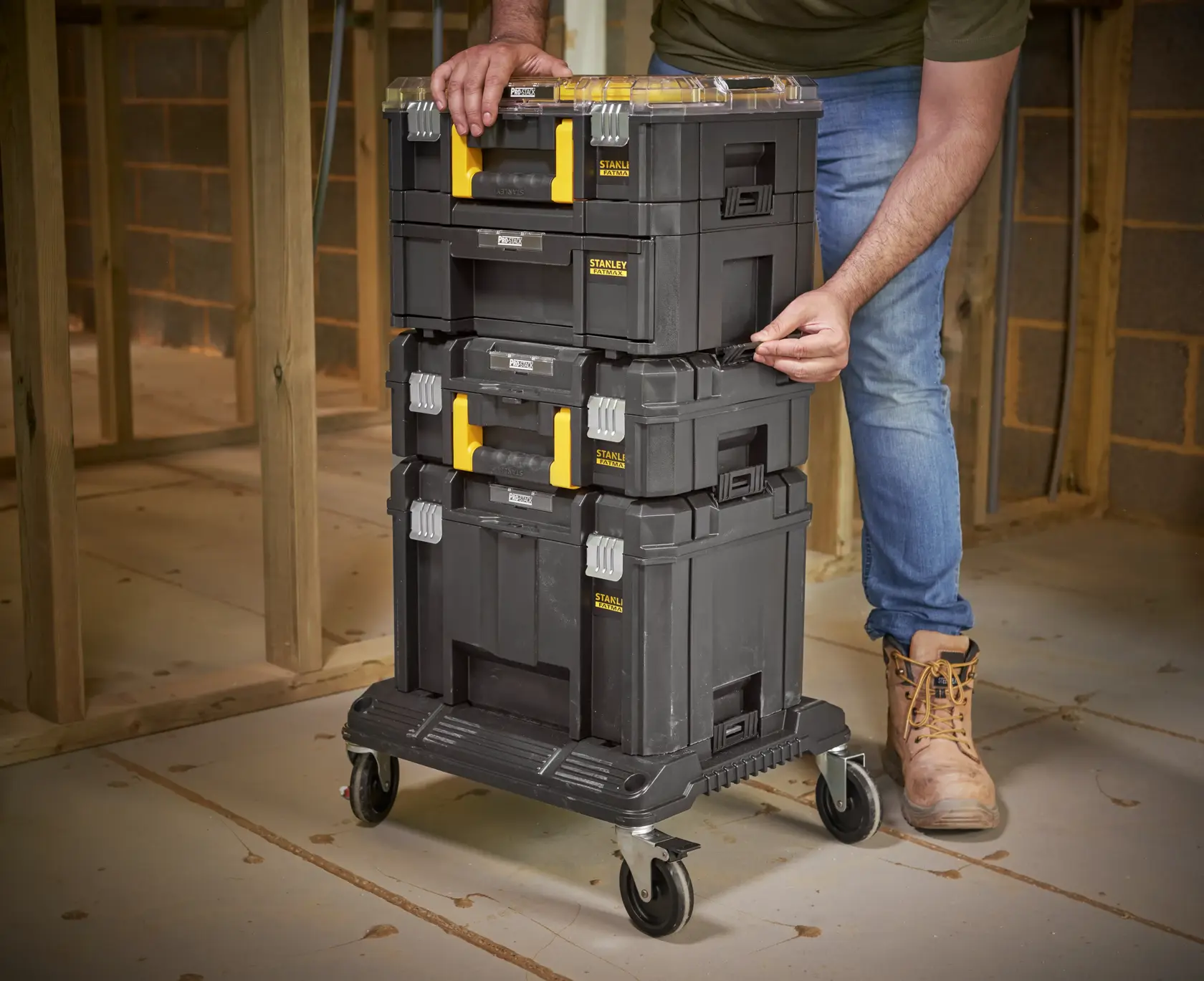 STANLEY FMST1-80107 stapelbare Werkzeugkästen mit gelben Griffen auf Rollwagen, Baustellenaufnahme.