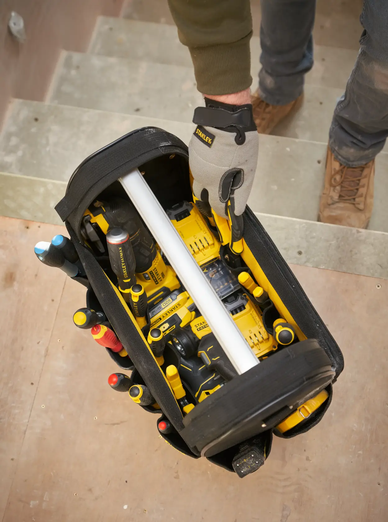 STANLEY FMST17626-1 photography of open tool bag with yellow power tools and hand tools viewed from above.