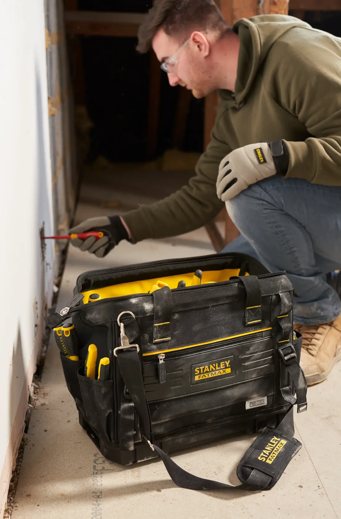 Photo of STANLEY FMST17627-1 tool bag with yellow accents, filled with hand tools, set on a worksite floor.