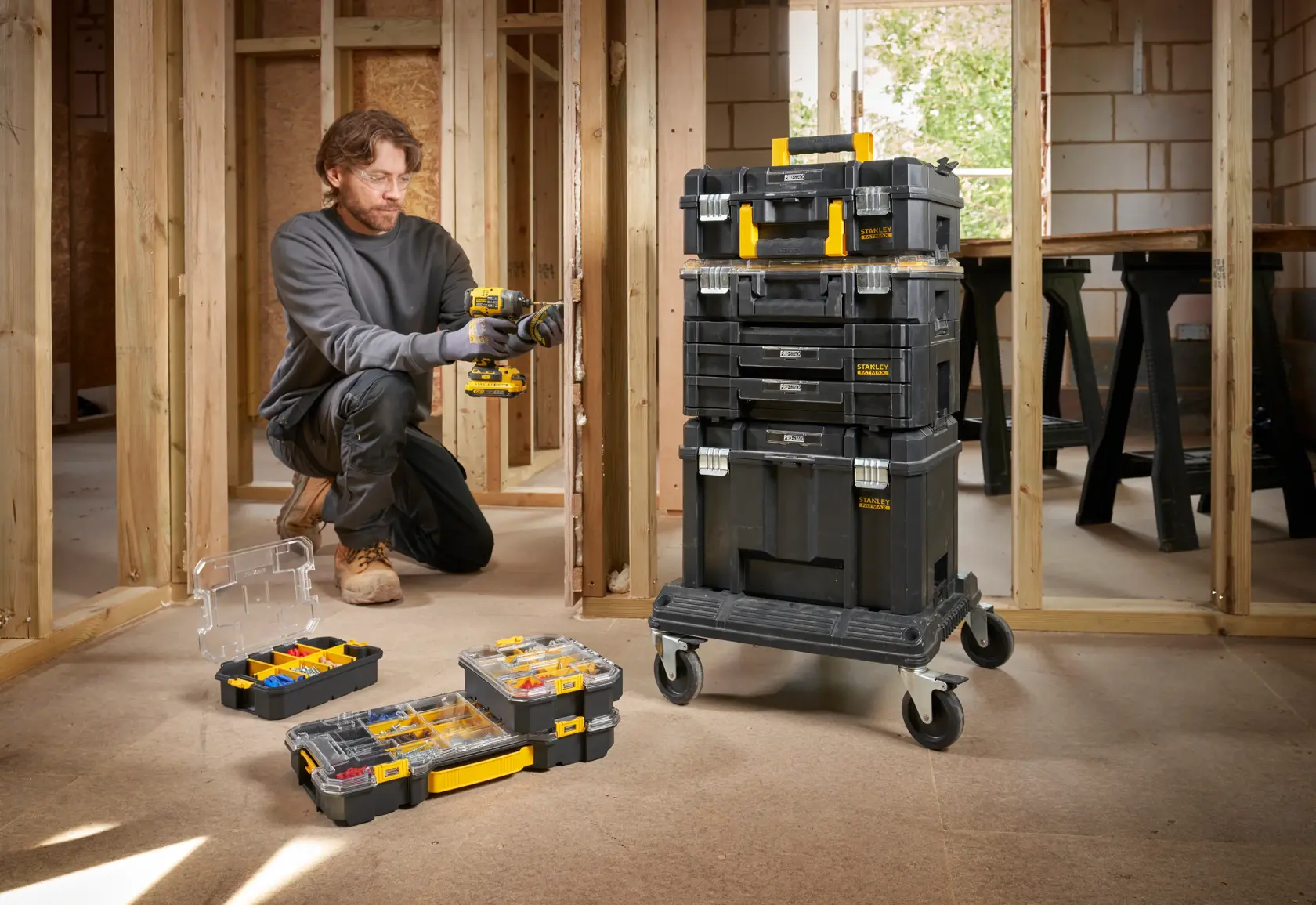 STANLEY FMST61150-1 stapelbare Werkzeugboxen auf Rollwagen mit offenen Organizern, abgebildet auf einer Baustelle.