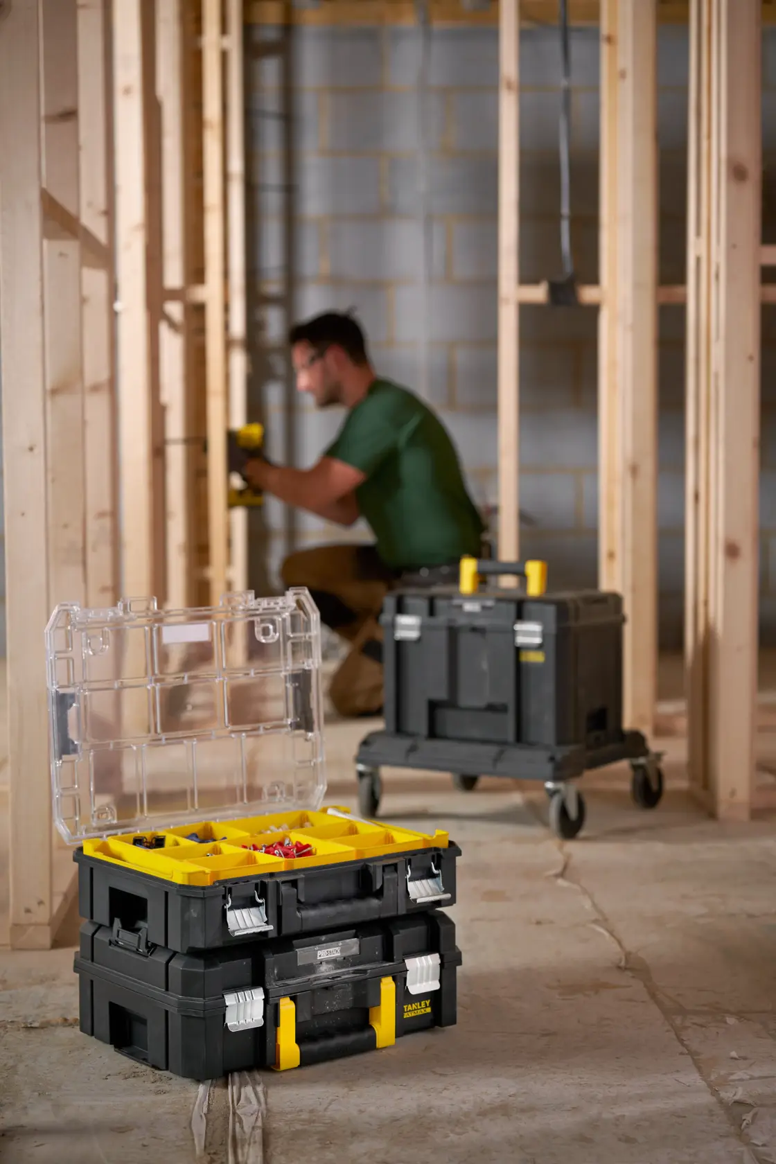 STANLEY FMST82967-9 stackable tool organizer with yellow compartments open on construction site floor.