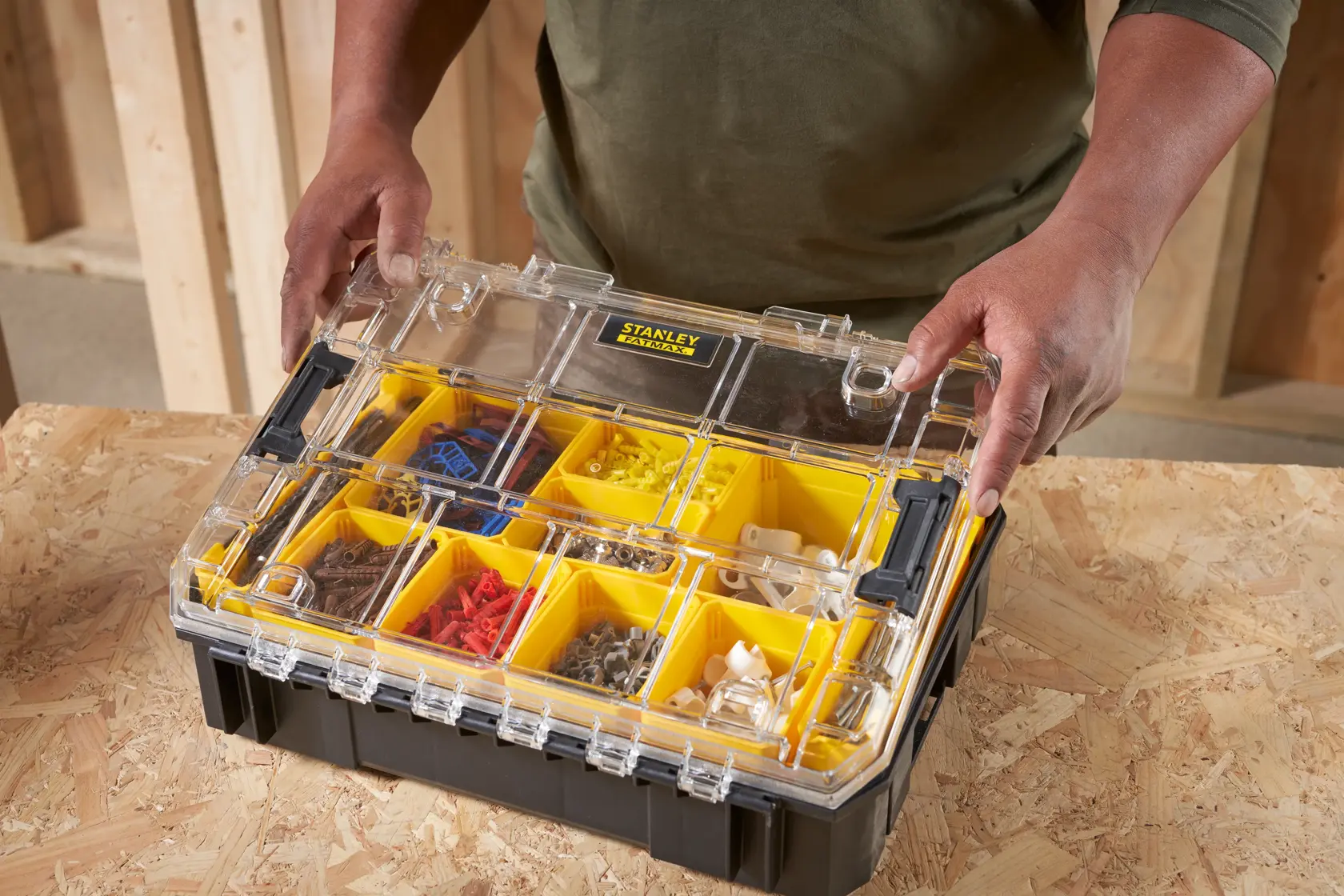 Photo of STANLEY FMST82967-9 organizer box with yellow compartments and clear lid on a workbench.
