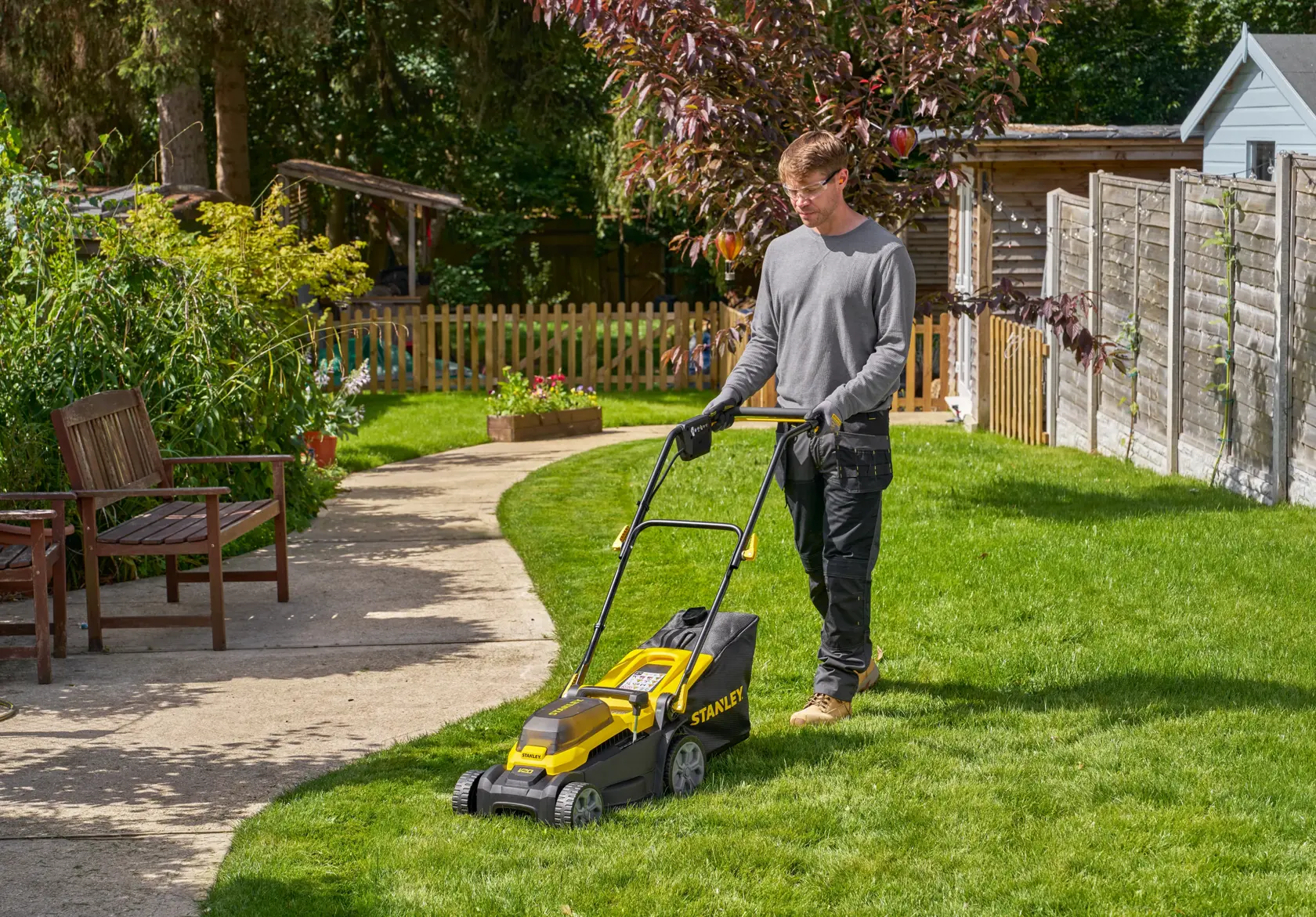 STANLEY SCMWP3401M1-XE Rasenmäher im Einsatz auf Gras im Garten, Seitenansicht.
