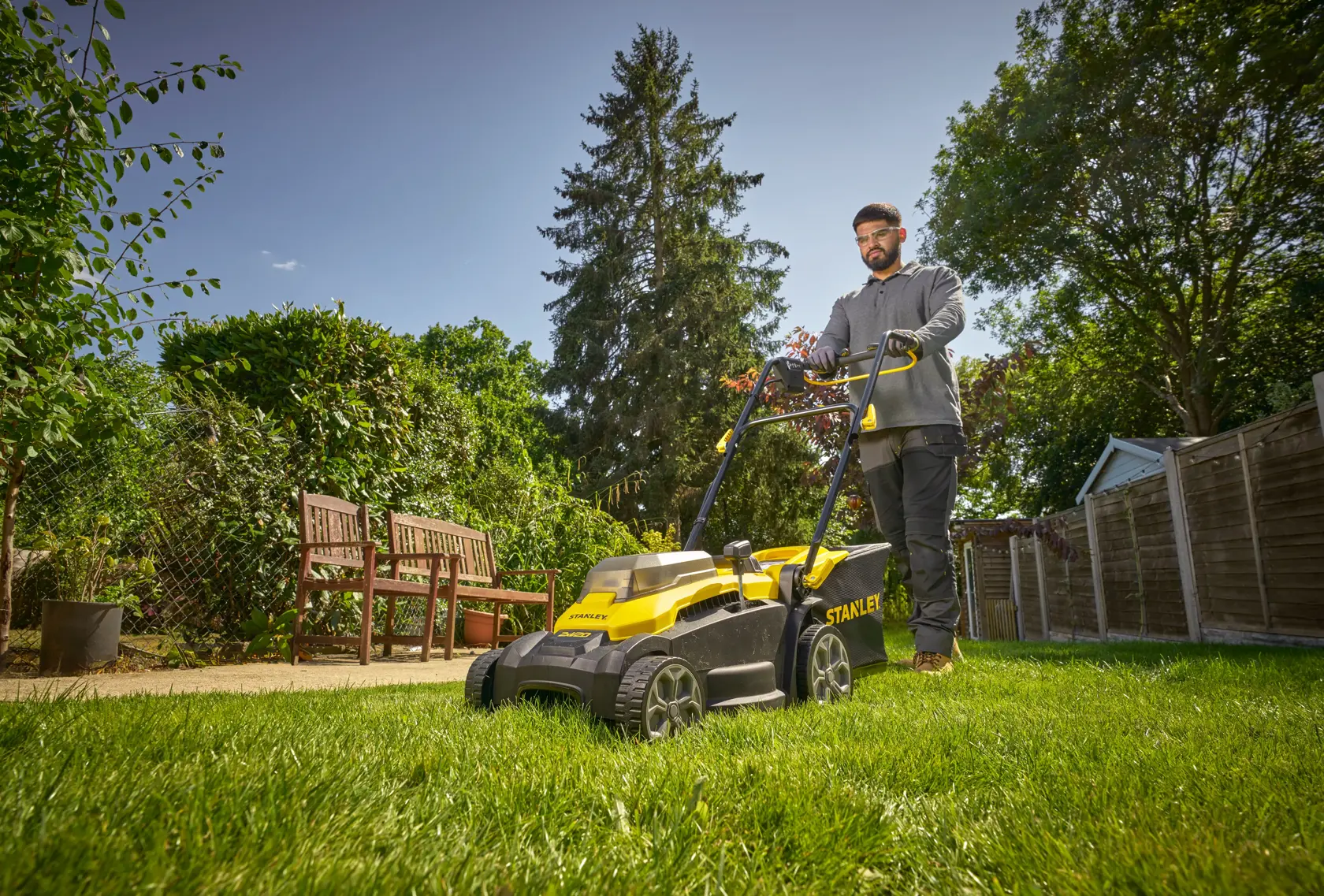 STANLEY SCMWP3701N Rasenmäher im Einsatz auf Rasen im Garten, Person schiebt Mäher, Aufnahme im Freien.
