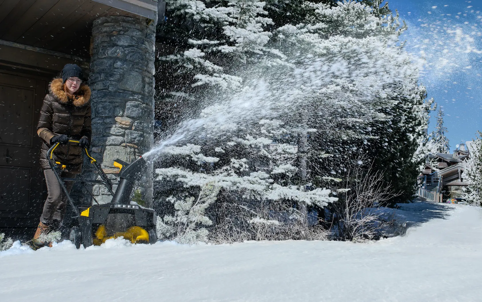 Foto der STANLEY SCSNP460R2 Schneefräse beim Schneeräumen auf der Einfahrt neben einem Haus im Winter.