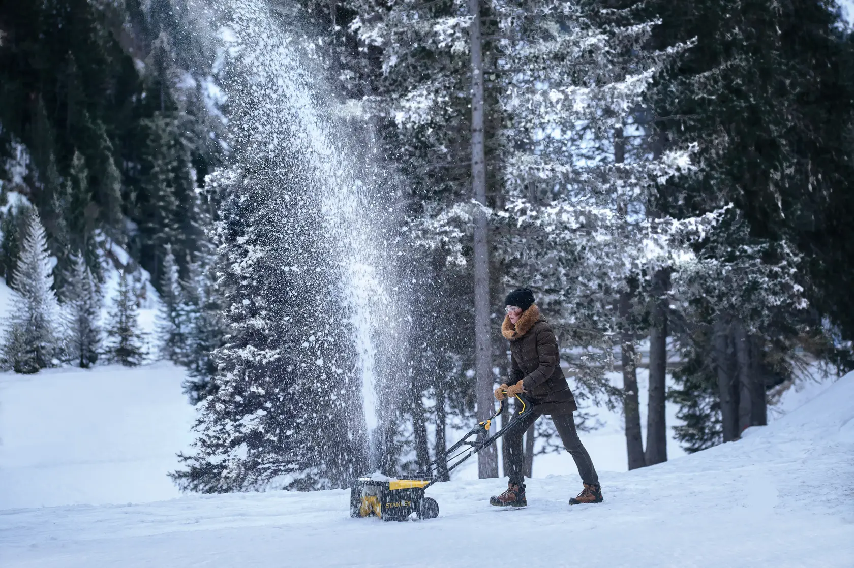 Foto des STANLEY SCSNP460R2 Schneefräse im Einsatz im Freien, räumt Schnee in einem verschneiten Wald.