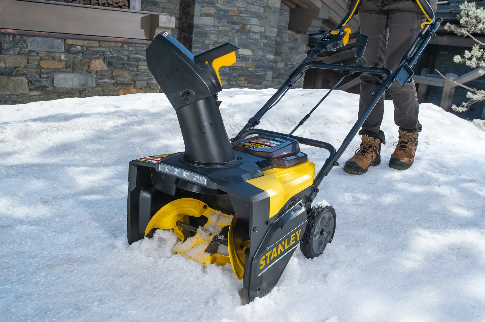 STANLEY SCSNP460R2 Schneefräse im Einsatz, gelb und schwarz, Vorderansicht, räumt Schnee draußen.