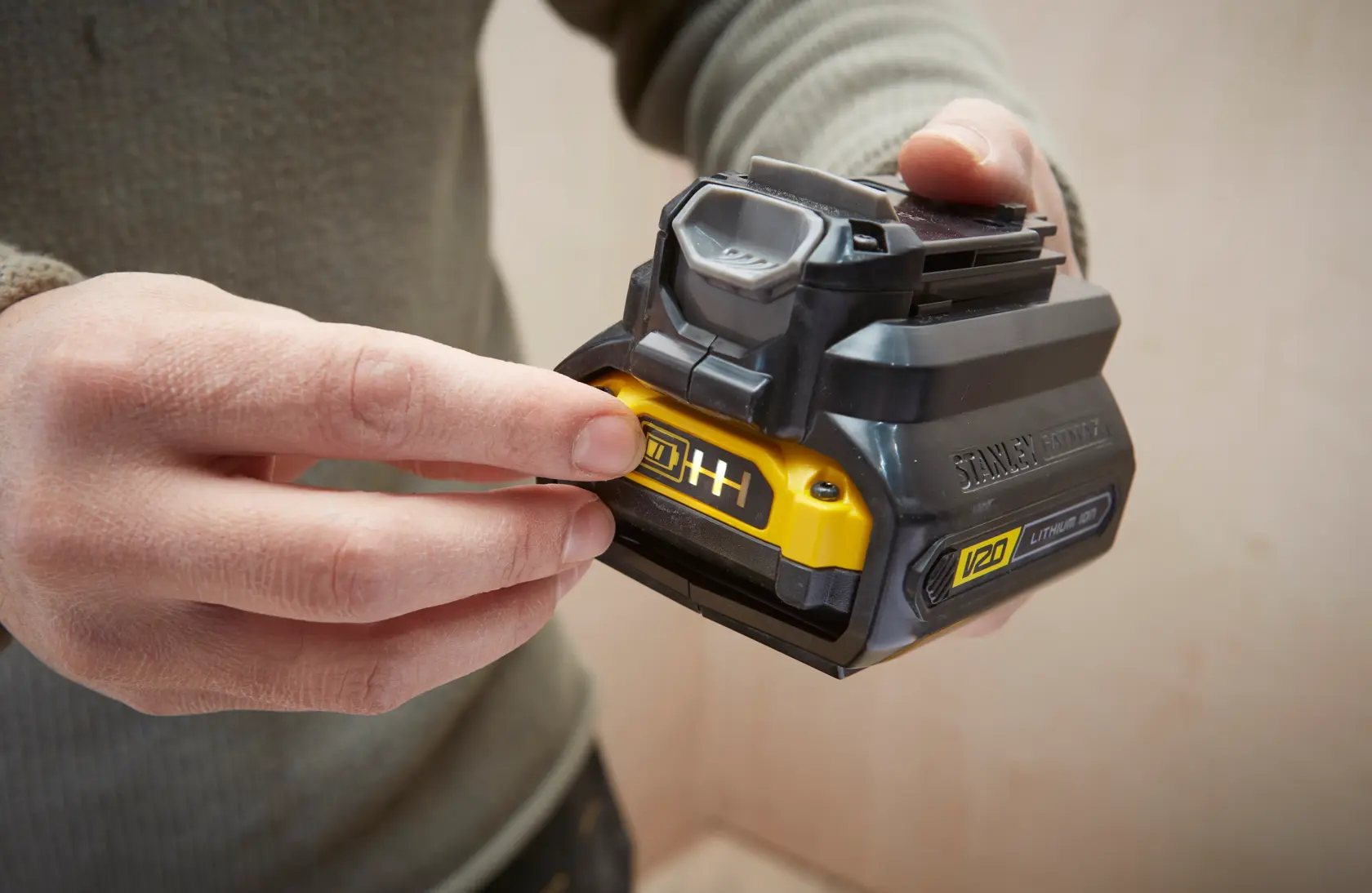 Photo of STANLEY SFMCB121D1 V20 lithium-ion battery, close-up in hand, showing yellow indicator panel.