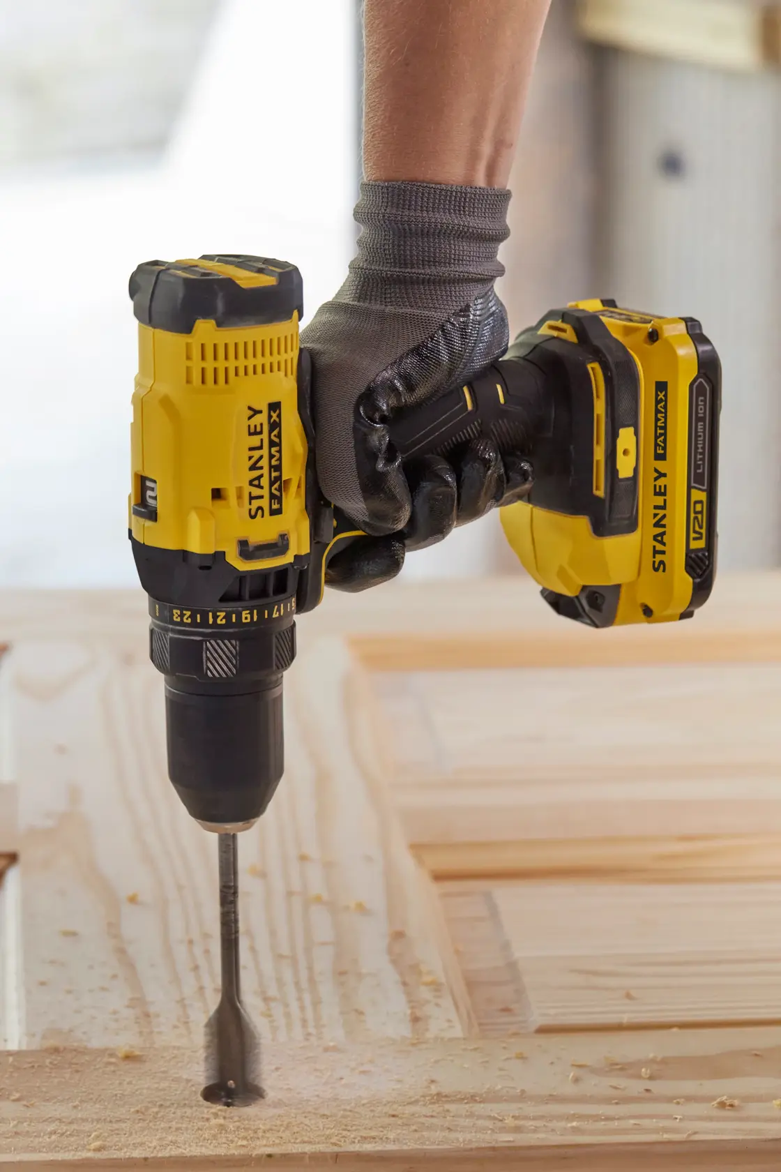 STANLEY SFMCD700C2K Akku-Bohrmaschine gelb-schwarz, im Einsatz, bohrt Holz mit großem Bohrer.