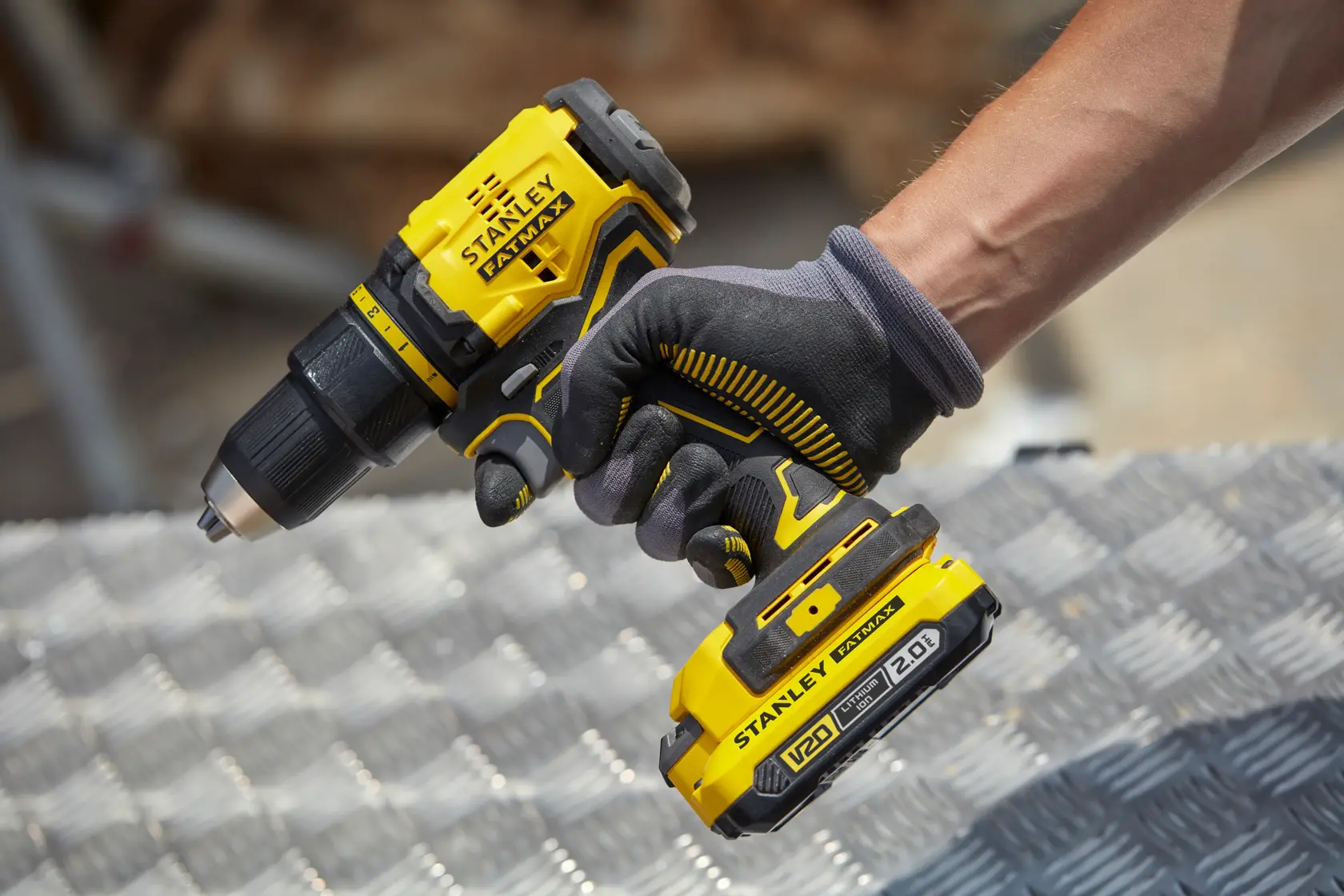Photo of STANLEY SFMCD710D2K cordless drill in use, yellow and black design, battery visible, held by gloved hand.