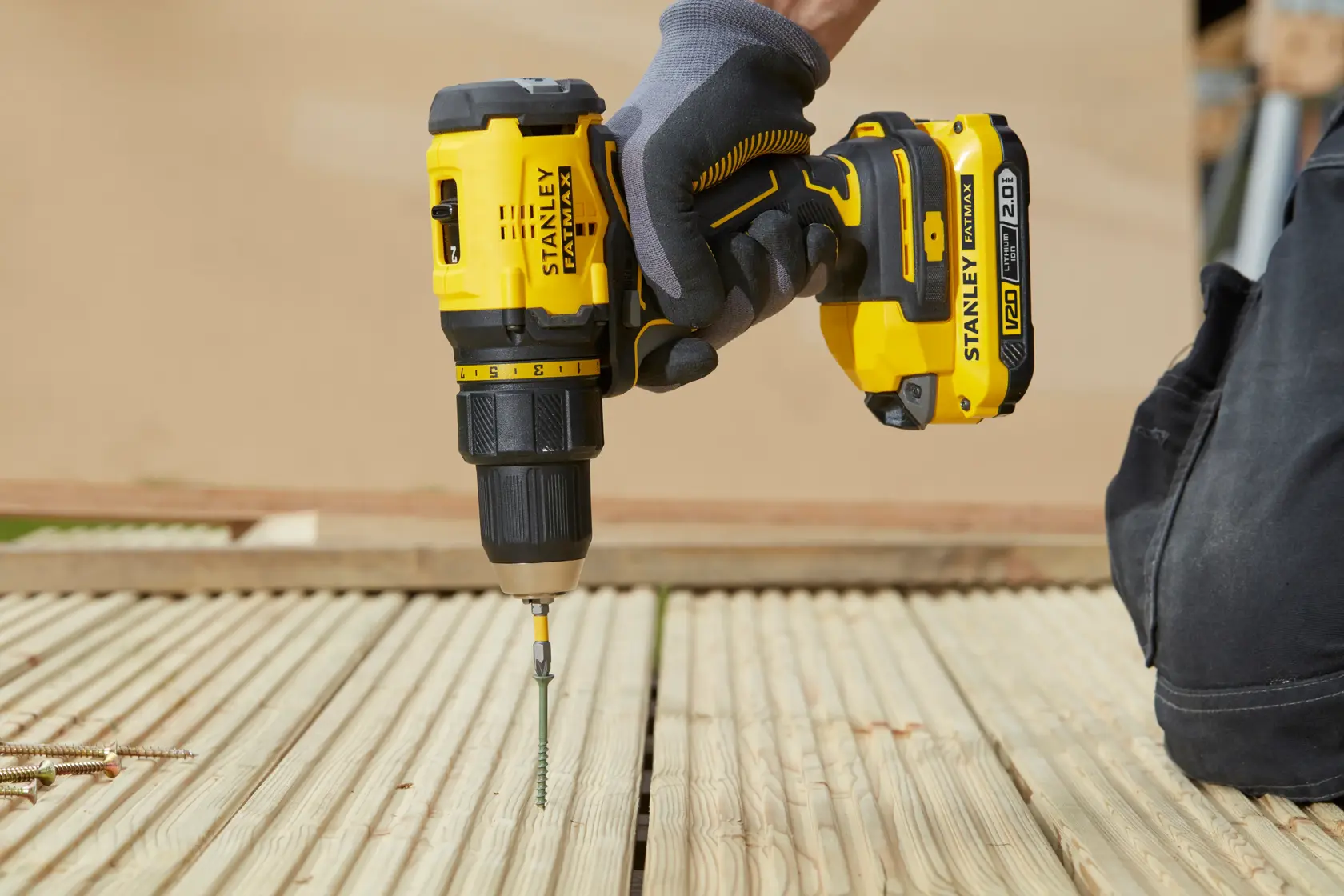 Stanley SFMCD710D2K cordless drill in use driving screw into wooden decking, side angle.
