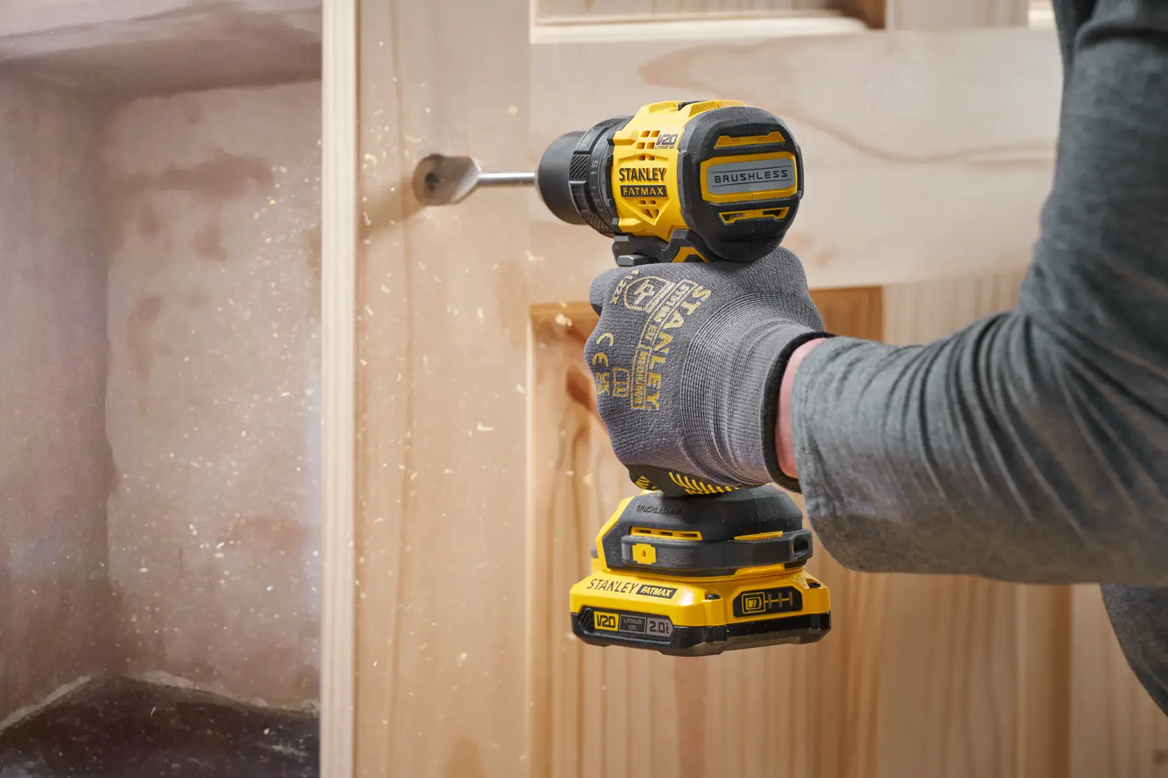 STANLEY SFMCD714B-XJ Akkubohrmaschine im Einsatz, Bohren in Holz, Seitenansicht, gelb-schwarzes Elektrowerkzeug.