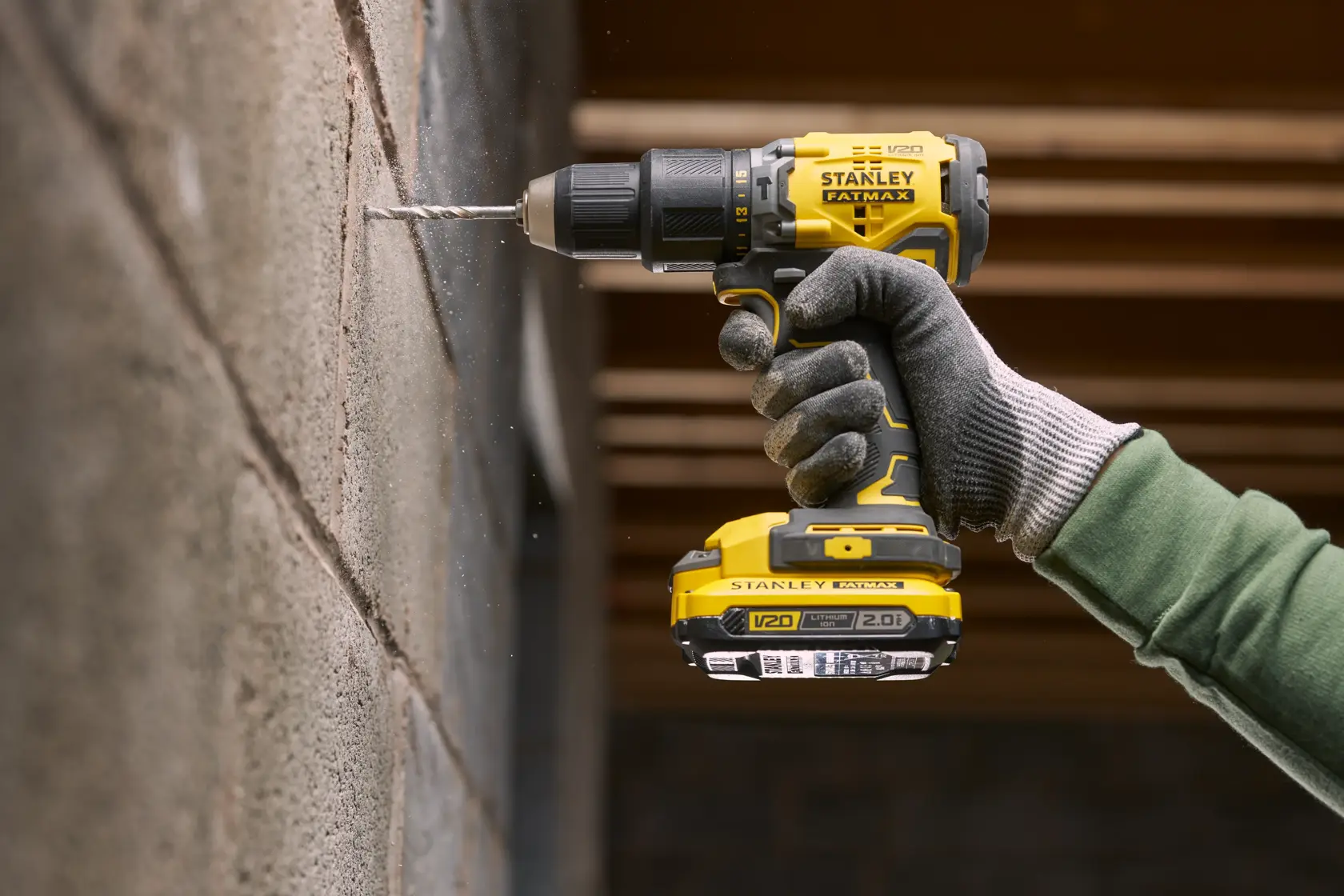 STANLEY SFMCD715D1K Akku-Bohrmaschine im Einsatz, Bohren in Betonwand, Seitenansicht, gelb und schwarz.